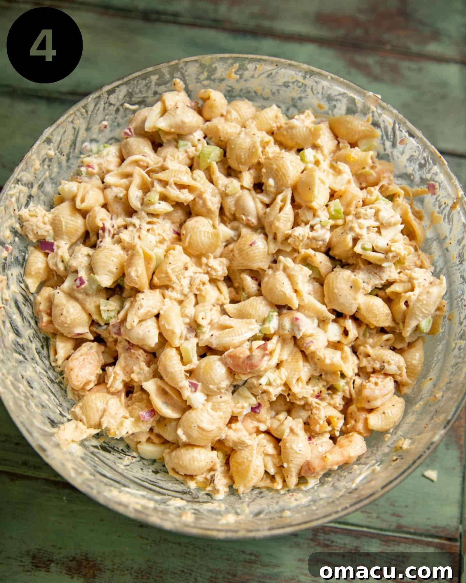 A large bowl of seafood pasta salad, fully mixed and ready to be chilled, showcasing the perfectly combined ingredients.