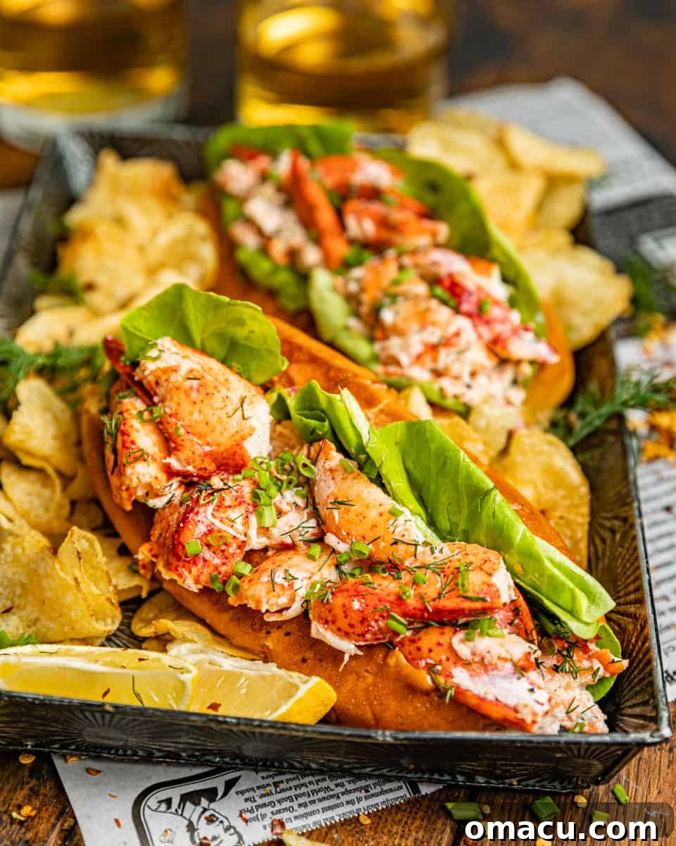 Two authentic New England Lobster Rolls served on a silver plate with crispy potato chips and a refreshing soda, ready to be enjoyed.