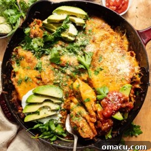 Cast iron skillet of Mexican stuffed shells topped with avocado and onion.
