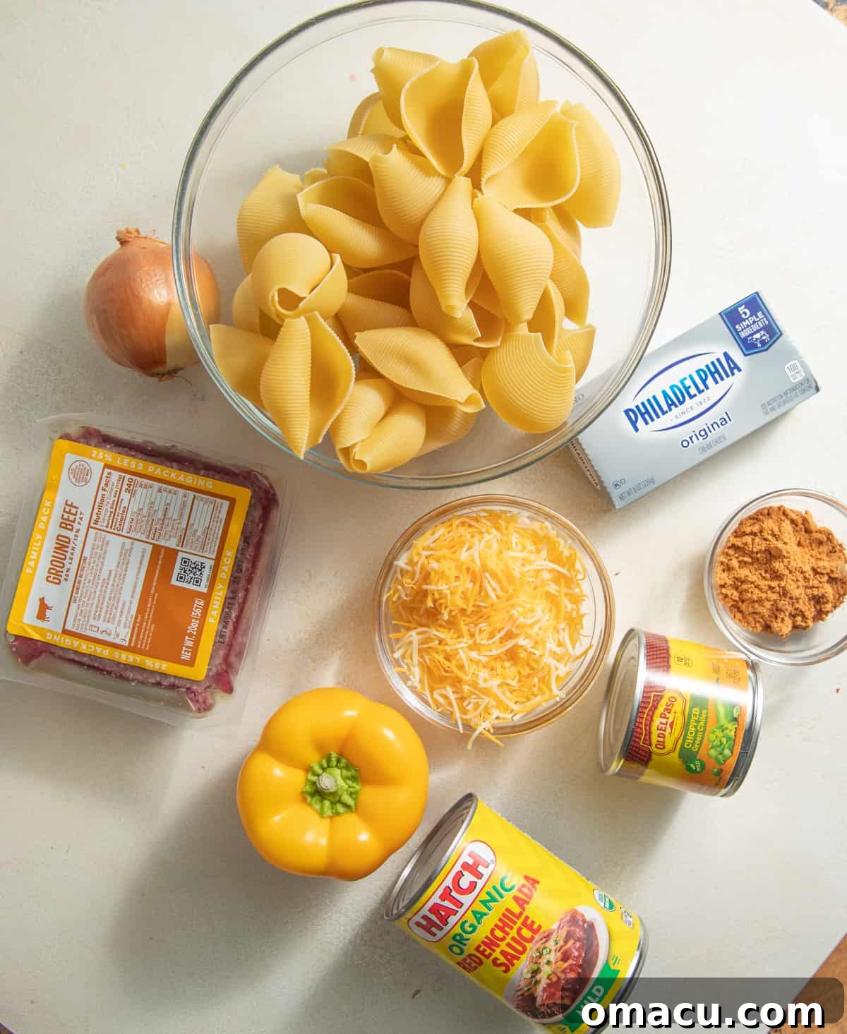 Ingredients laid out for making Mexican stuffed shells, including ground beef, spices, cheese, and pasta.