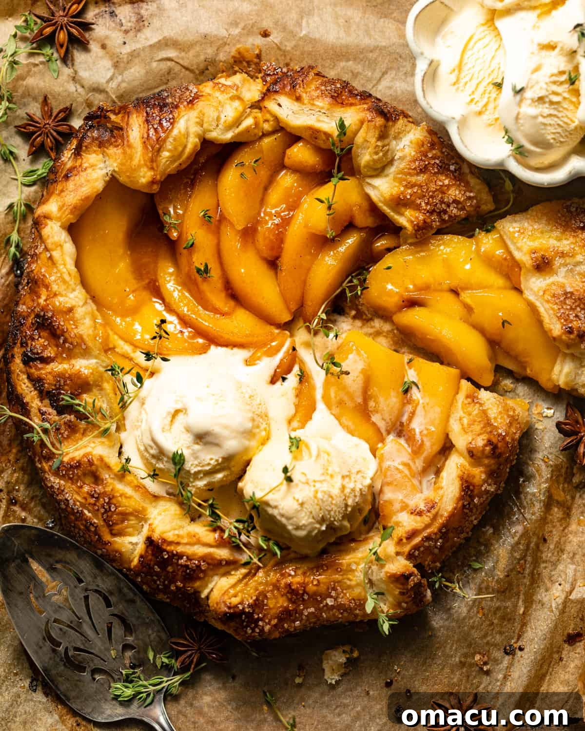 Rustic peach galette with two scoops of vanilla ice cream on top, ready to be served.