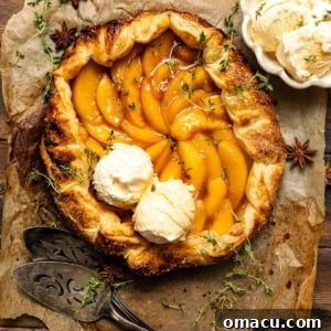 Rustic peach galette with two scoops of vanilla ice cream on top.