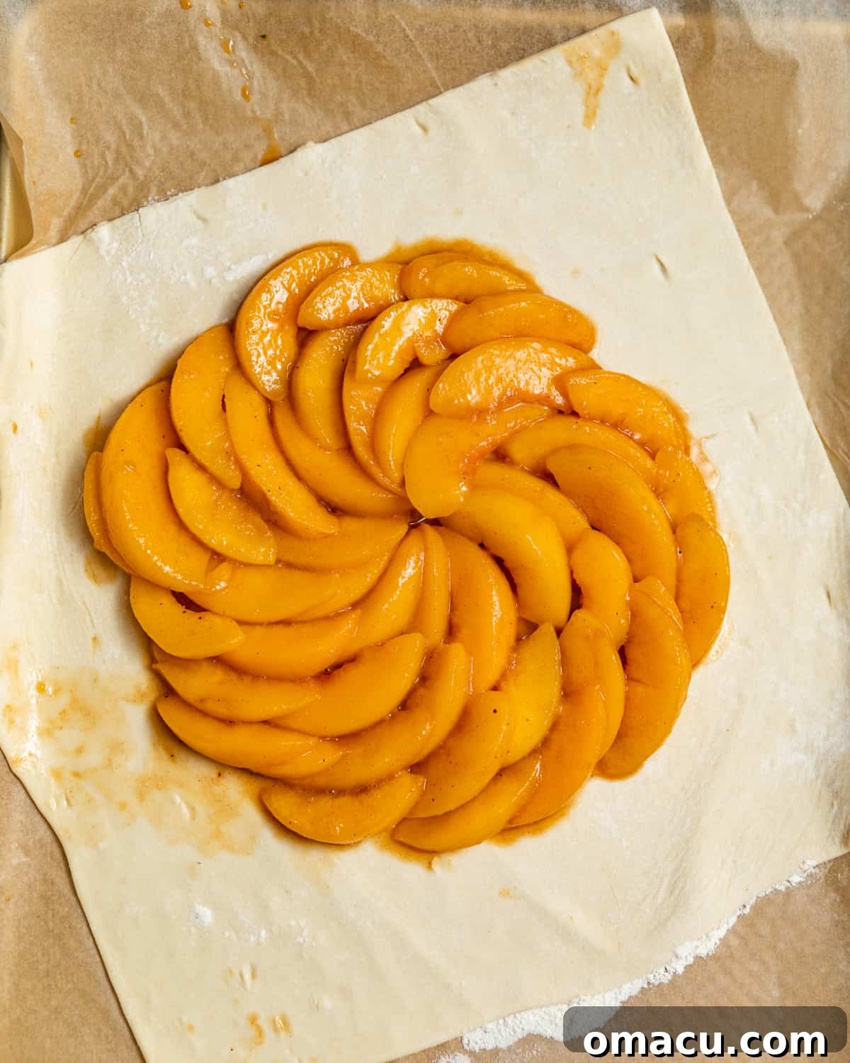 Syrupy peach slices fanned out in a circle in the center of a square of puff pastry.