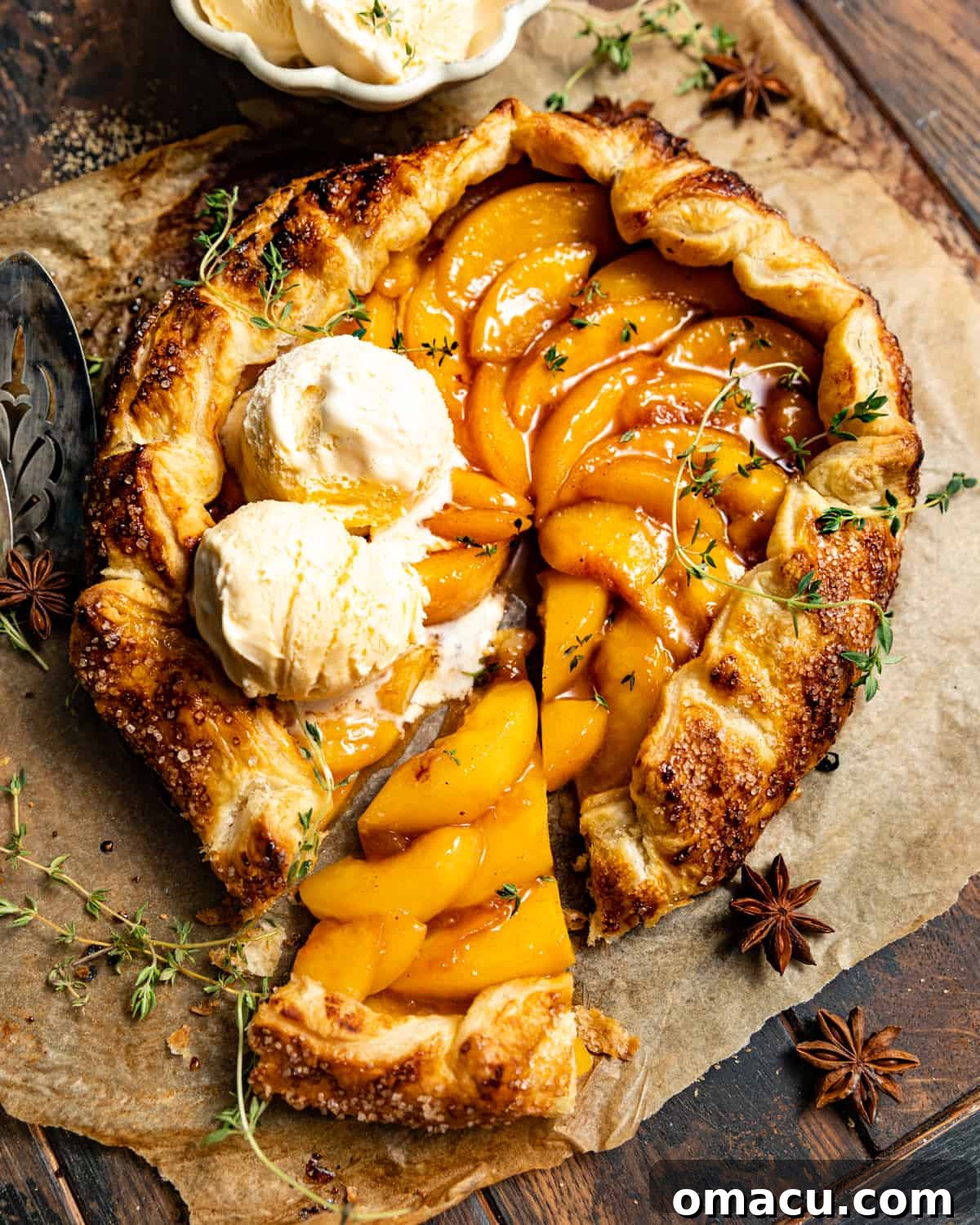 Rustic peach galette with two scoops of vanilla ice cream on top, ready for digging in.