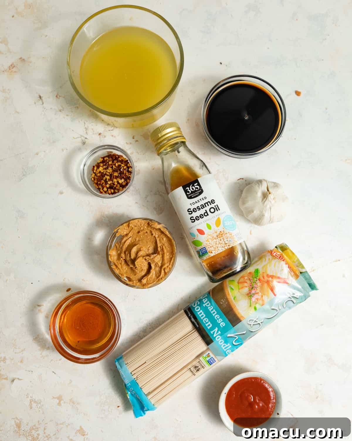 Ingredients to makes spicy peanut noodles on a white surface.