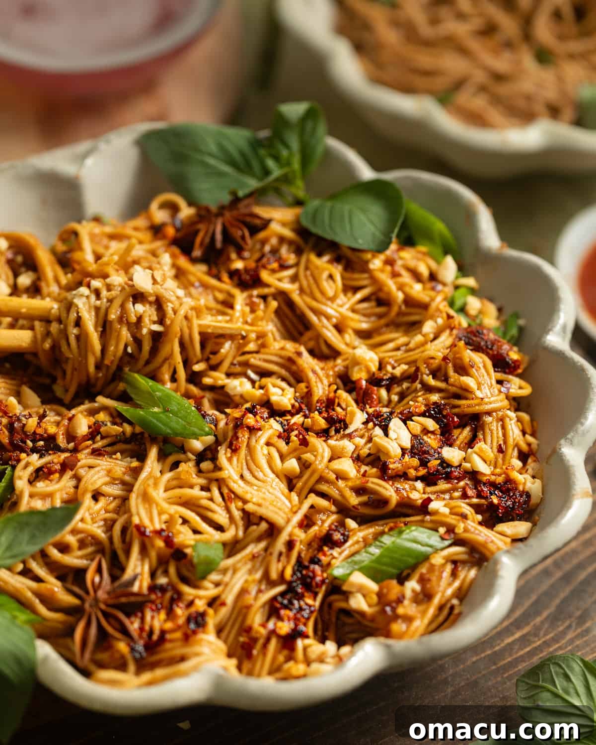 A pair of chopsticks in a bowl of spicy peanut noodles.