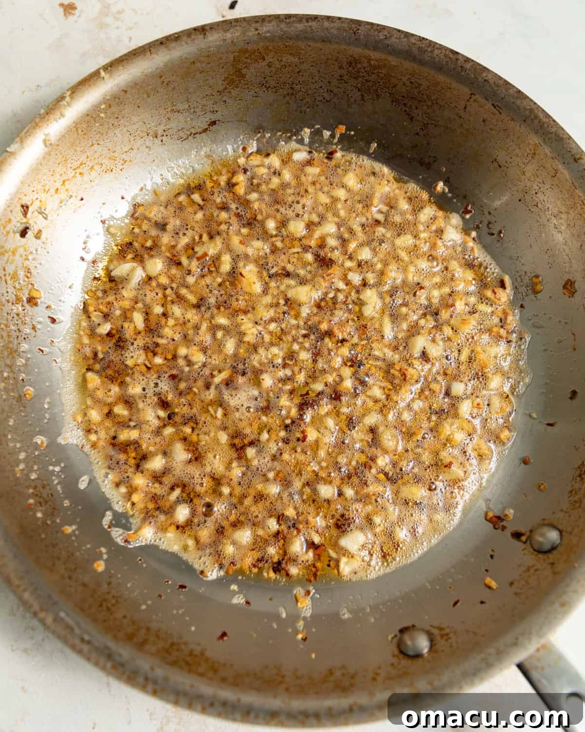 Garlic and ginger infusing sesame oil in a saucepan.