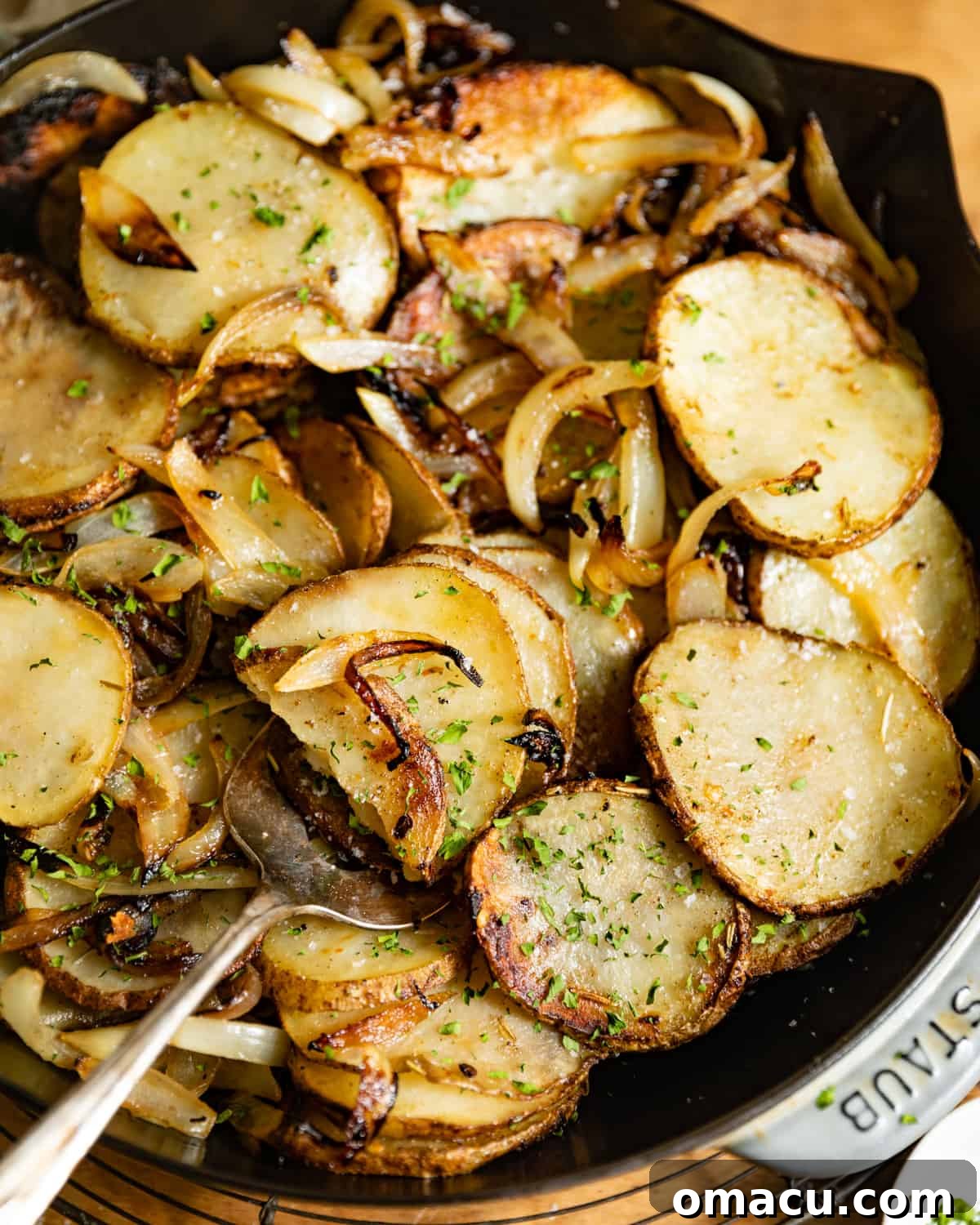 A generous serving of fried sliced potatoes and onions resting in a rustic cast iron skillet, golden and inviting.