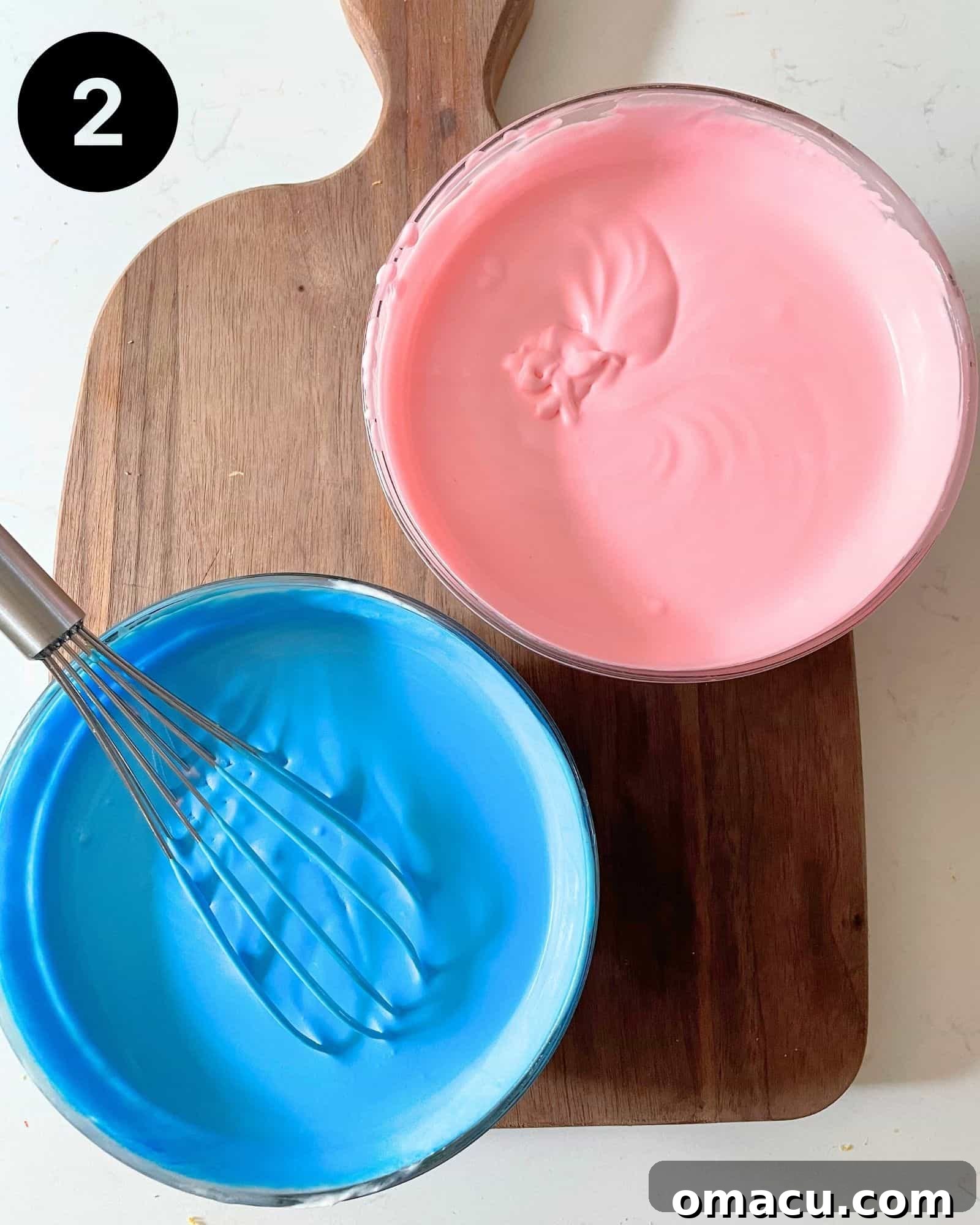 Two separate bowls filled with fluffy cotton candy ice cream base, one colored vibrant pink and the other a playful blue, ready to be swirled together.