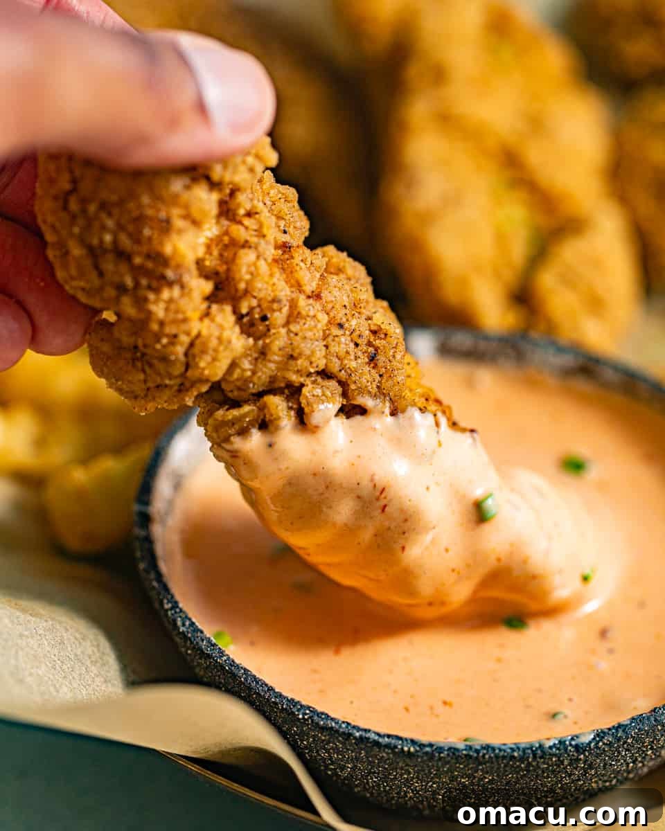 A golden-brown chicken tender perfectly dipped in a dollop of creamy Boom Boom Sauce.