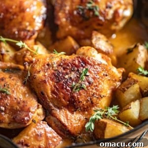 Maple dijon chicken thighs with chopped potatoes in a cast iron skillet.