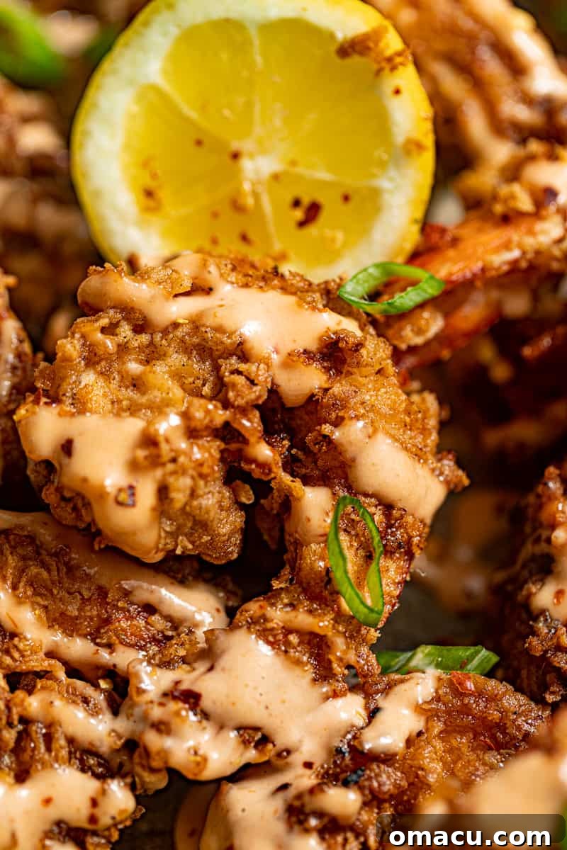 Close-up of a perfectly fried Boom Boom shrimp with a lemon wedge and fresh parsley, highlighting its golden crispiness.
