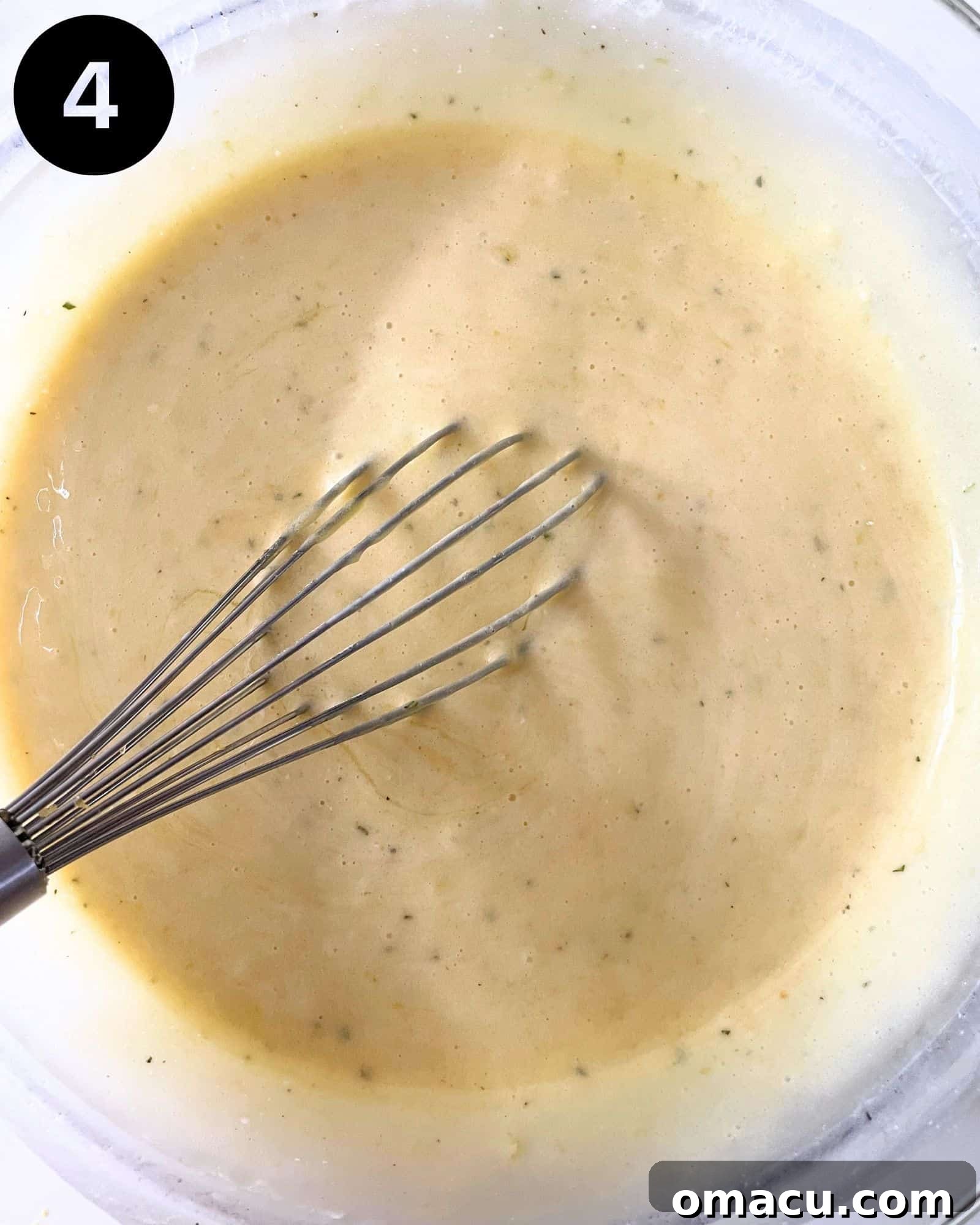 The fully combined cake batter, a smooth and luscious mixture, rests in a mixing bowl with a whisk, ready for baking.