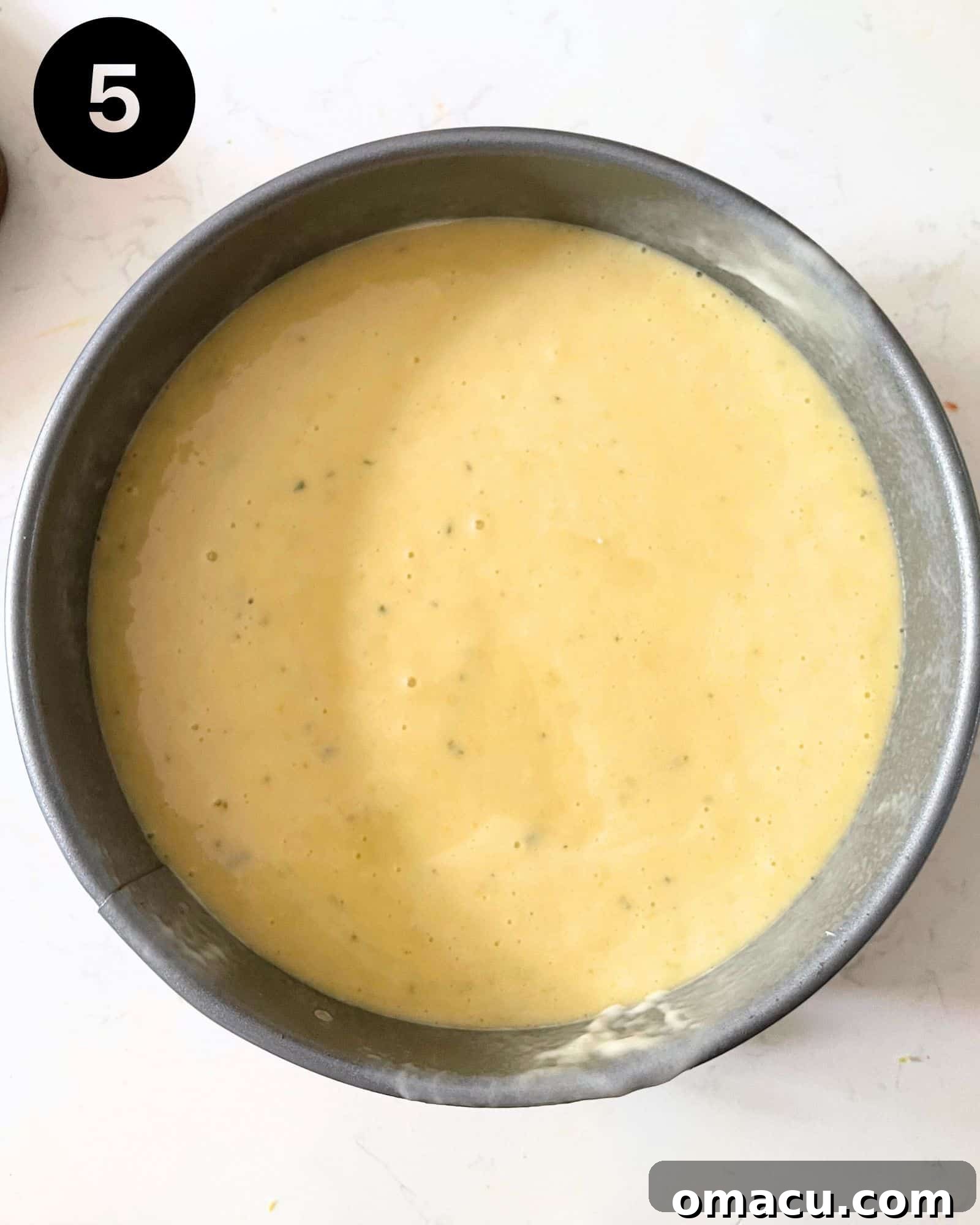 The smooth cake batter is poured evenly into a round cake pan, ready to be baked into a delicious dessert.