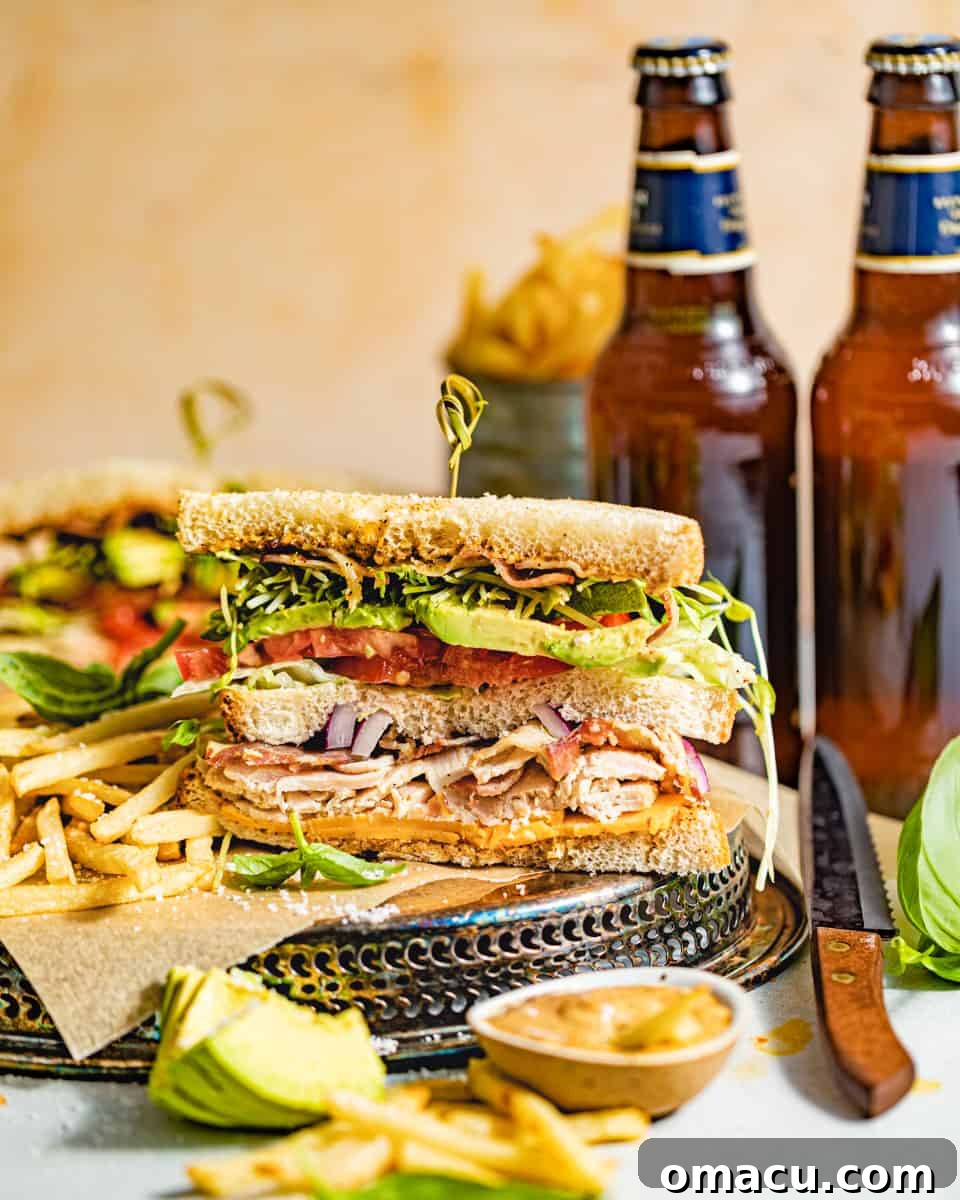 A perfectly cut California Club Sandwich served with golden french fries and a side of creamy chipotle mayo.