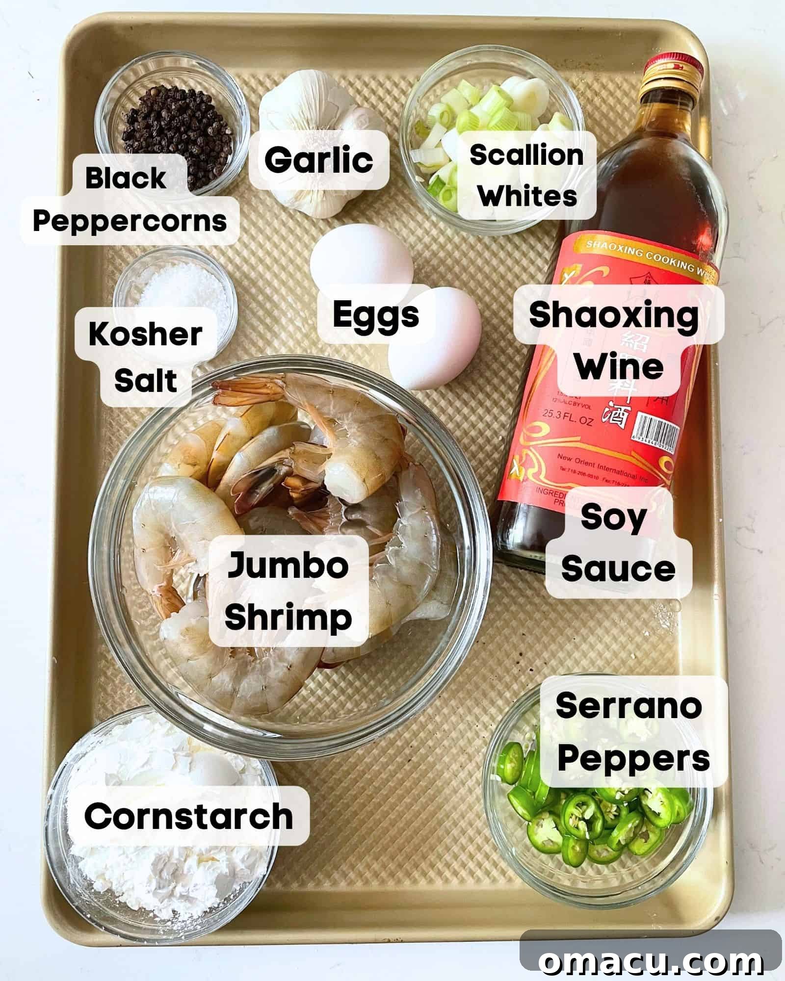 A visual guide to ingredients for Salt and Pepper Shrimp: jumbo shrimp, Shaoxing wine, soy sauce, garlic cloves, whole black peppercorns, kosher salt, an egg, cornstarch, serrano peppers, fresh ginger, and scallions, all neatly arranged on a baking sheet.