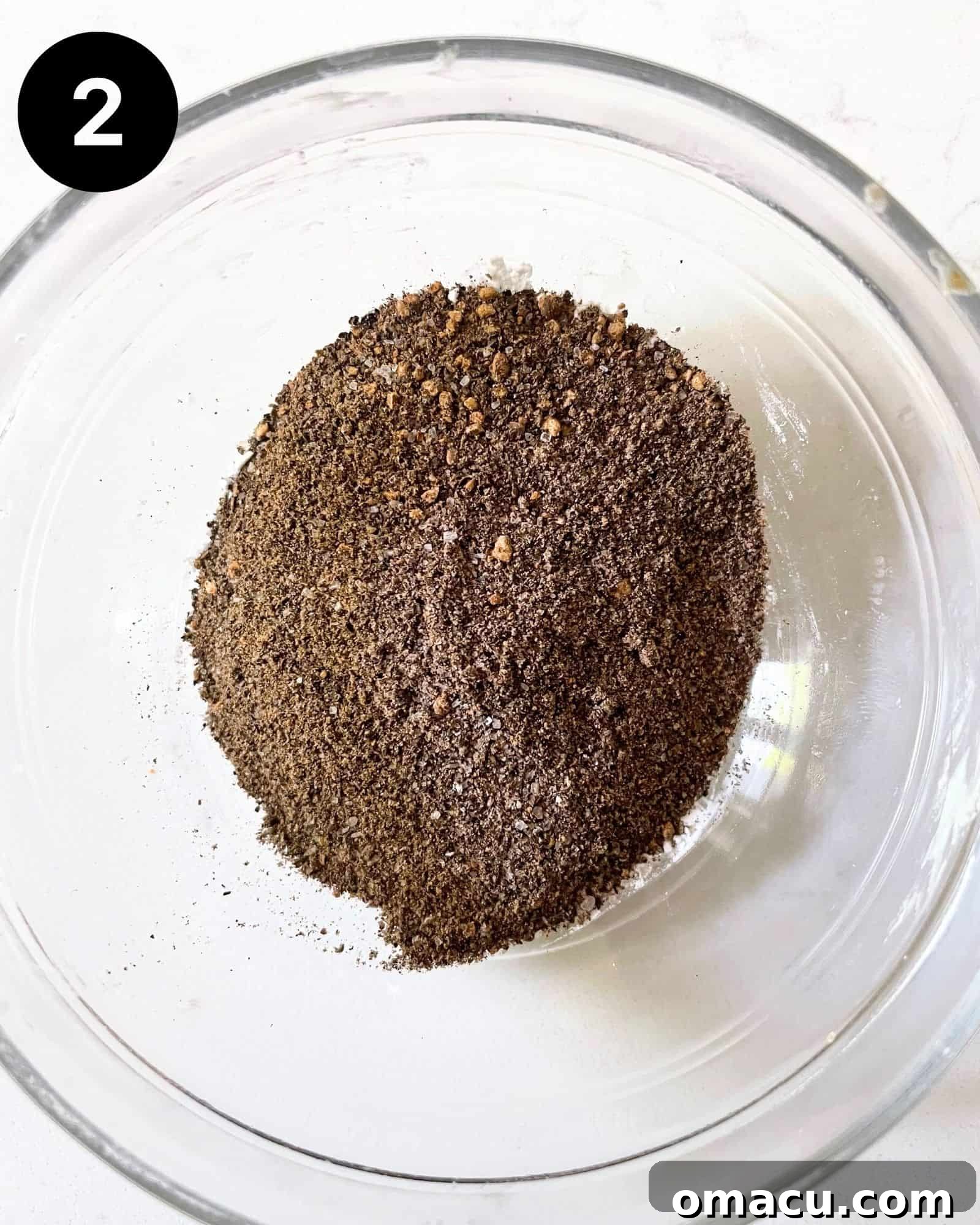 A small bowl containing the freshly ground black peppercorns and kosher salt blend, ready for use.