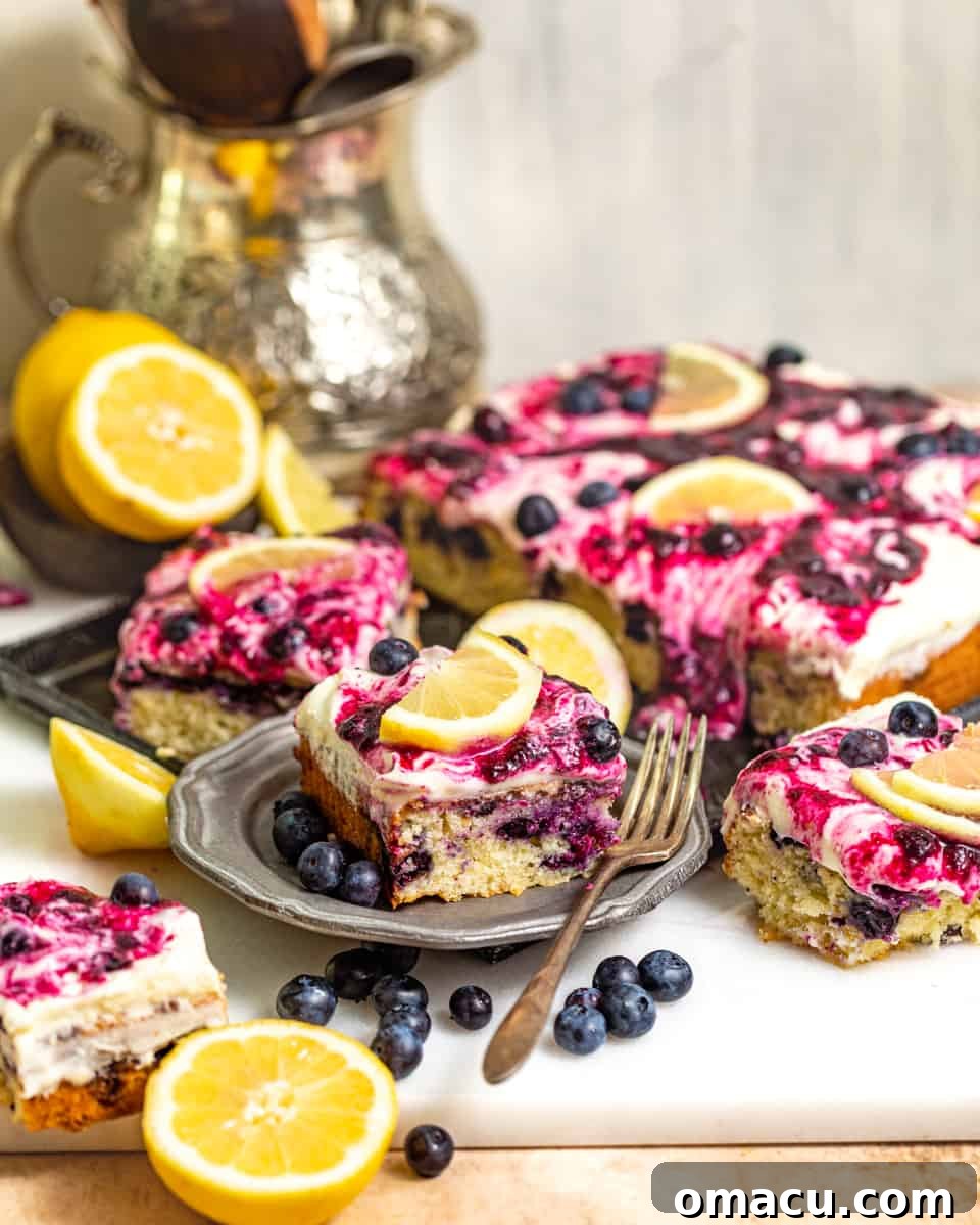 A glorious lemon blueberry sheet cake, perfectly cut into squares, garnished with fresh blueberries and lemon slices, and drizzled with homemade blueberry sauce.