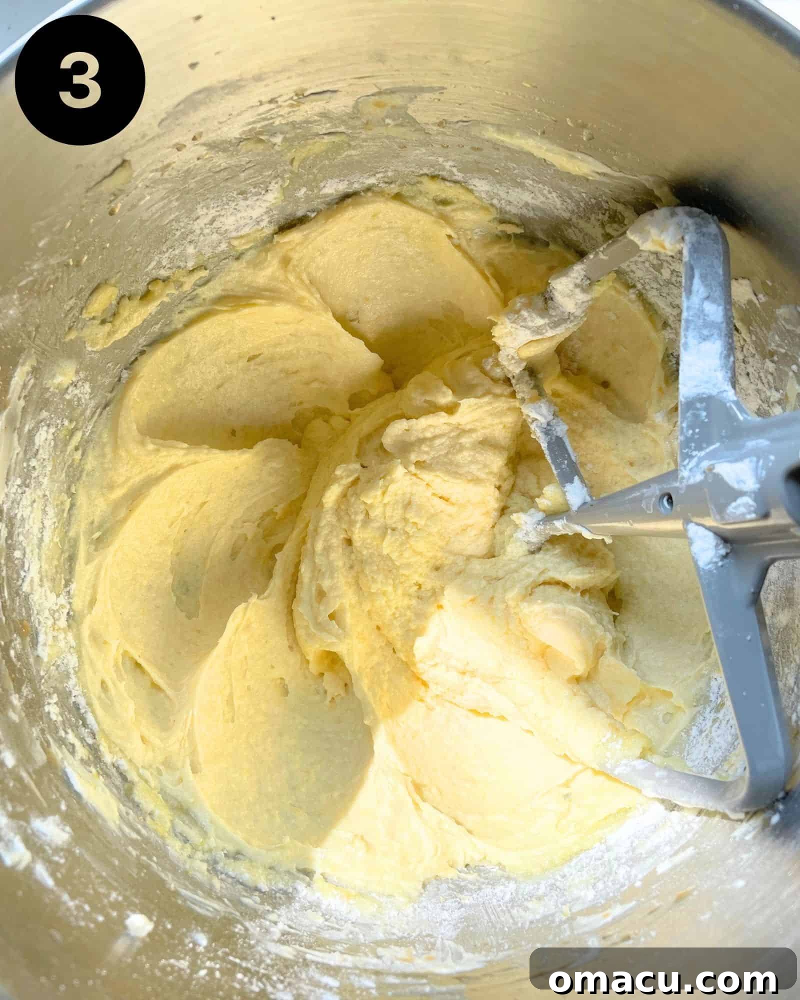 Lemon blueberry cake batter in a stand mixer bowl with the paddle attachment, looking creamy and well-combined.