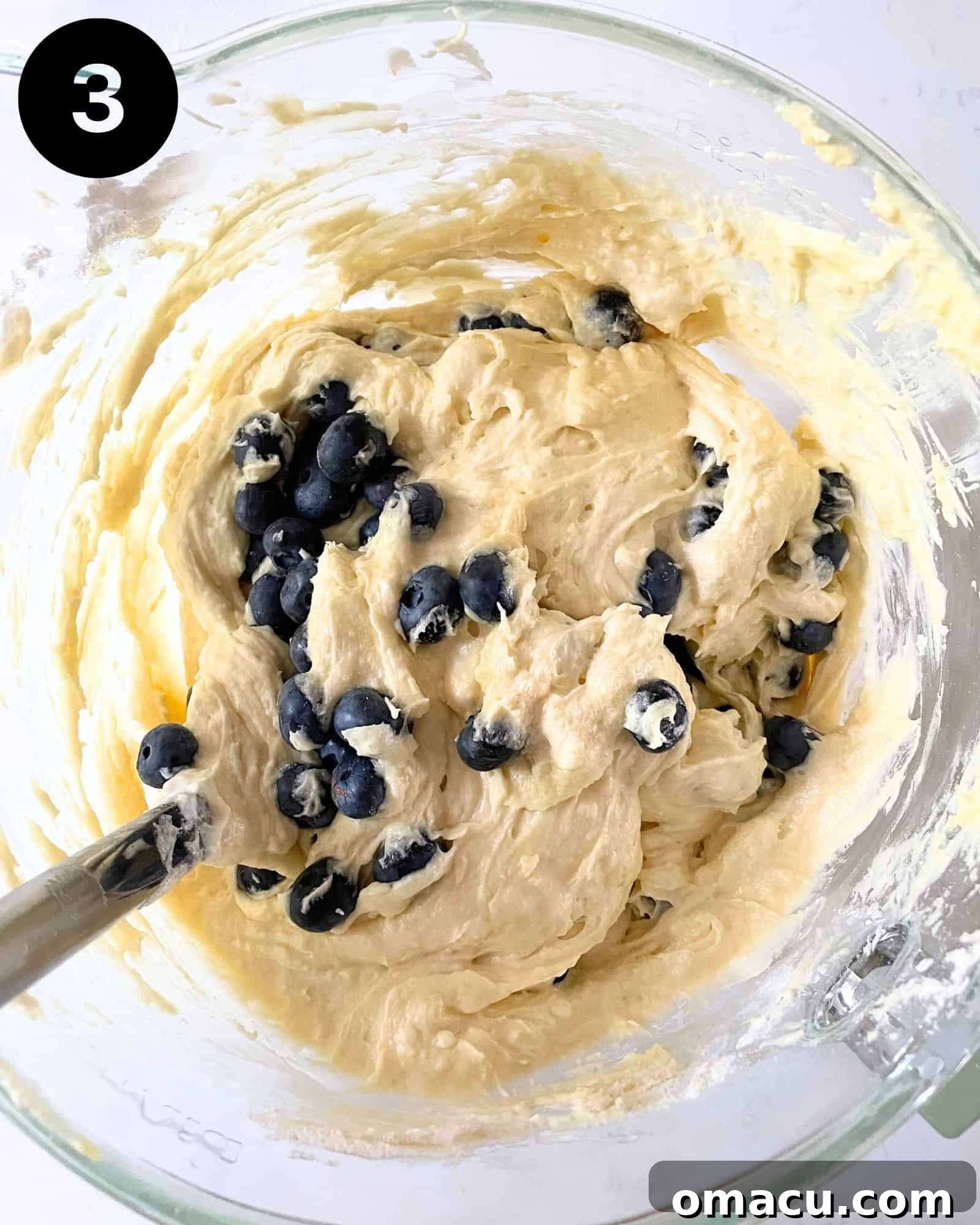 Cake batter in a bowl with fresh blueberries gently folded in, ready for baking.