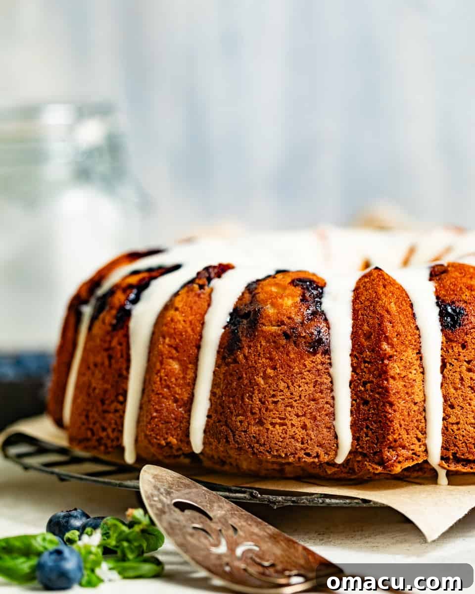 Finished blueberry pound cake on a wire rack, beautifully adorned with a generous cream cheese glaze on top.