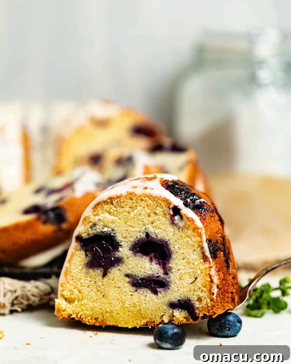 A perfectly sliced piece of blueberry pound cake resting on a cake server, ready to be enjoyed.