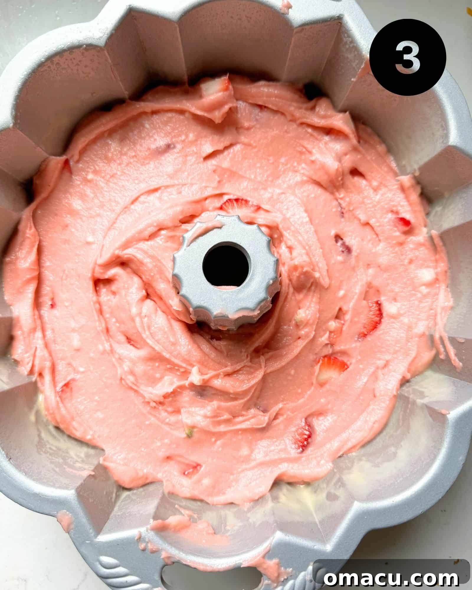 Strawberry pound cake batter neatly poured into a 12-cup bundt pan, ready for baking in the oven.