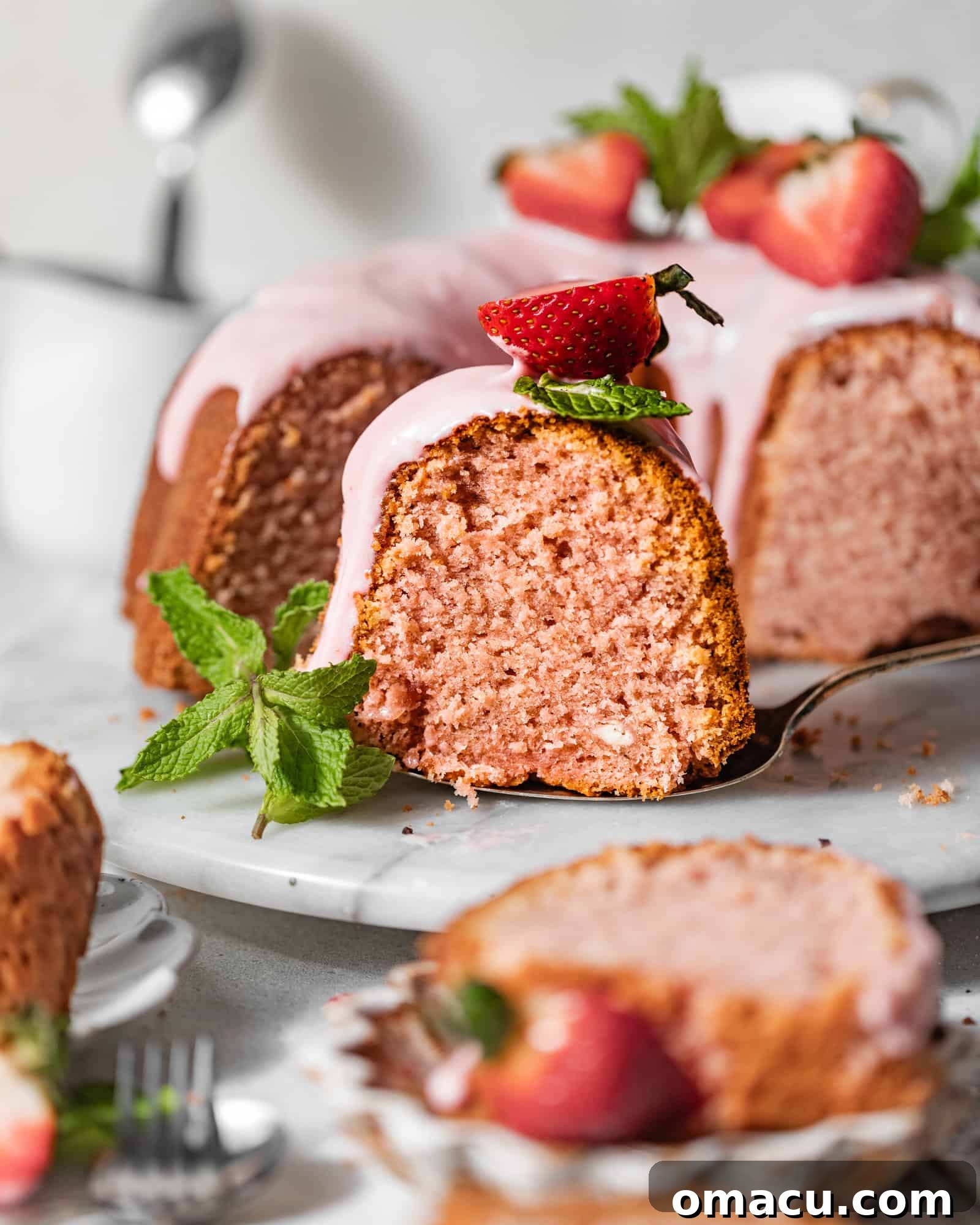 A perfectly sliced strawberry pound cake elegantly presented on a marble serving plate, garnished with fresh mint leaves and plump fresh strawberries.