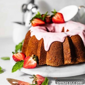 strawberry pound cake on a serving tray garnished with fresh strawberries and strawberry glaze.