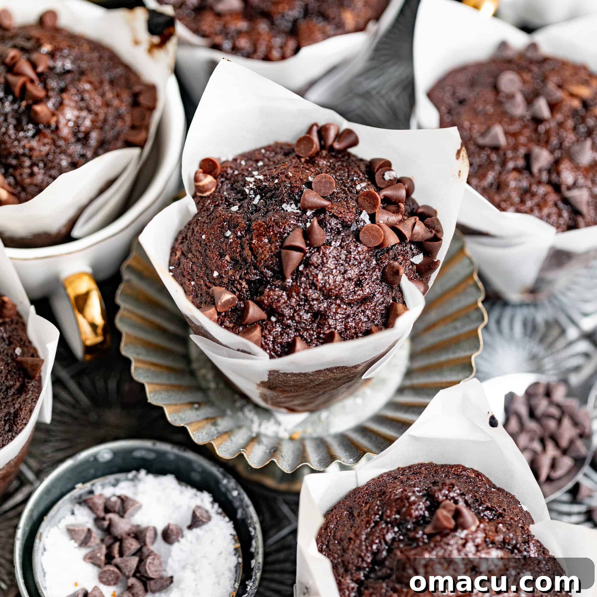 Freshly baked brownie muffins arranged beautifully on a silver serving tray, garnished with flake salt and mini chocolate chips.