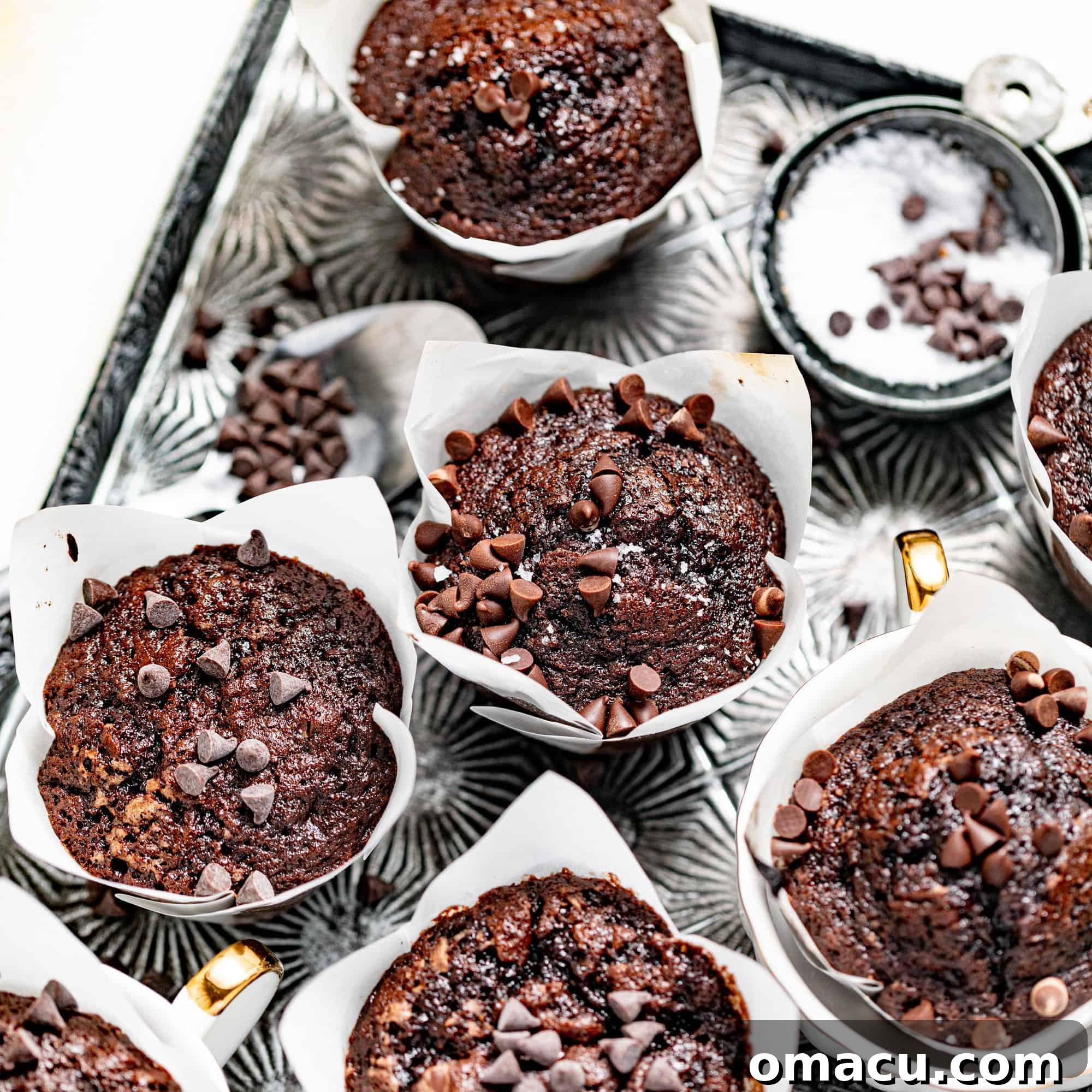 A serving tray filled with delectable brownie muffins, surrounded by loose chocolate chips, ready to be enjoyed as a delightful treat.