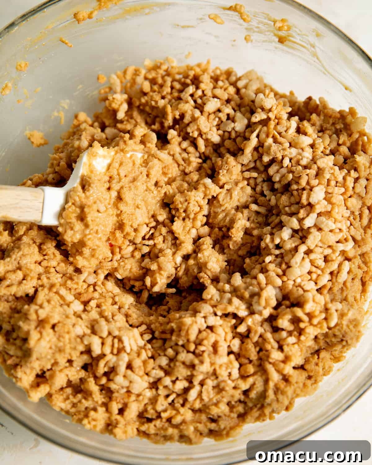 A spatula in a mixing bowl of Rice Krispie peanut butter truffle filling.