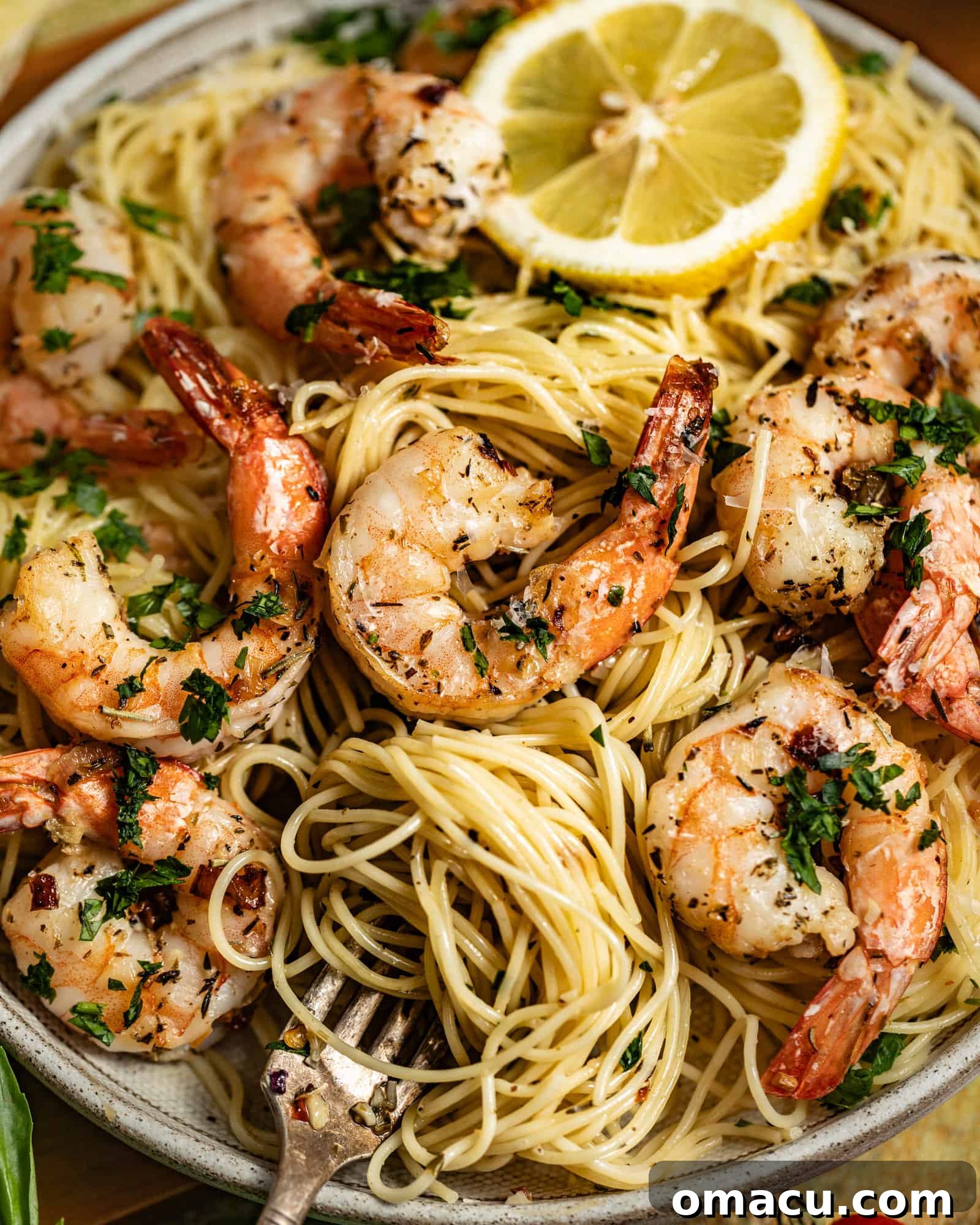 A serving of shrimp scampi with angel hair pasta ready to be enjoyed, garnished with fresh herbs and Parmesan cheese.