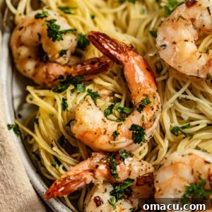 A top-down view of Shrimp Scampi with Angel Hair Pasta in a serving bowl, garnished with fresh herbs and lemon.