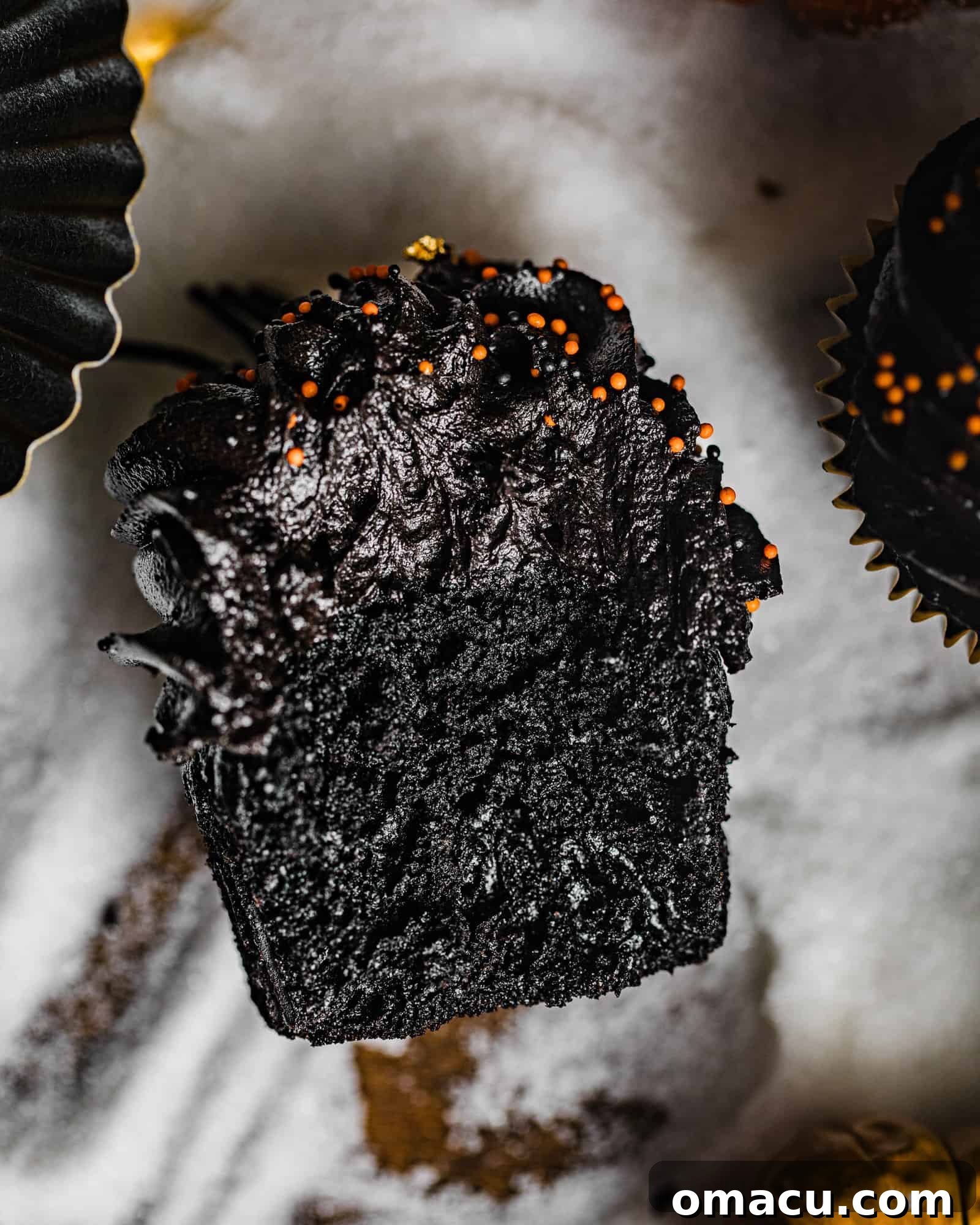 An up-close photo of a black velvet cupcake cut in half, revealing its moist, dark interior.