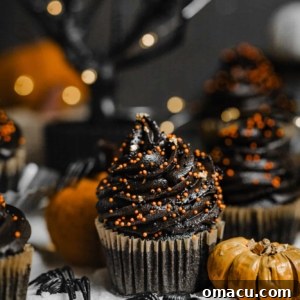 A black velvet cupcake in front of a black tree with pumpkins and fake spiders.