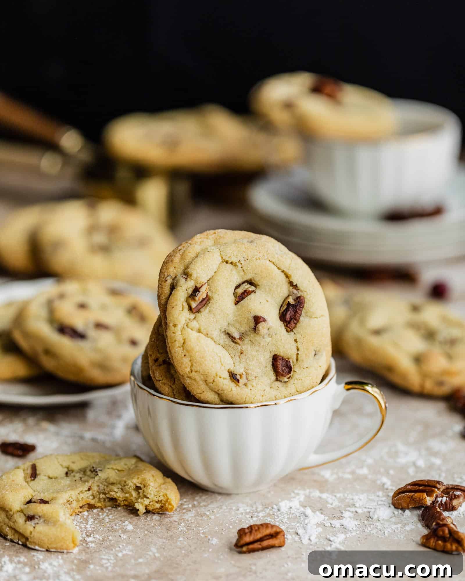 Vanilla Bean Butter Pecan Cookies served in a teacup, with more cookies casually placed behind it.