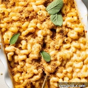 A top-down view of a baking dish filled with rich, golden-brown smoked gouda mac and cheese, beautifully garnished with fresh herbs, ready for serving.