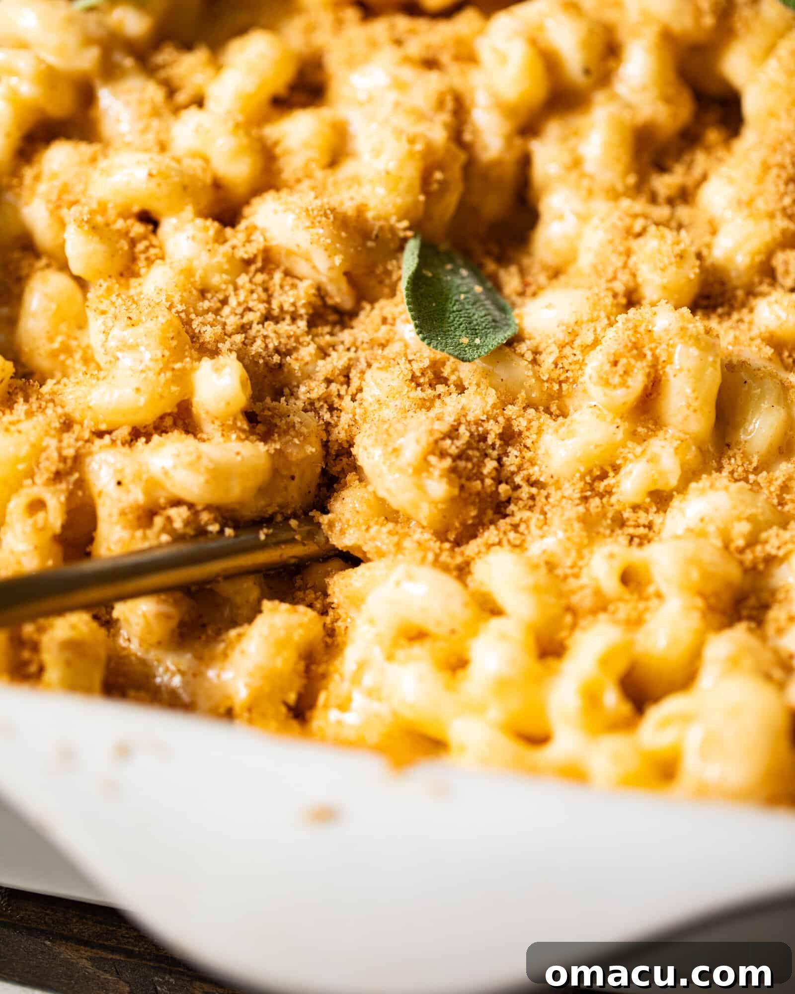 A mesmerizing close-up photo of creamy, perfectly cooked macaroni noodles generously coated in a rich, velvety cheese sauce, freshly scooped from a baking dish.