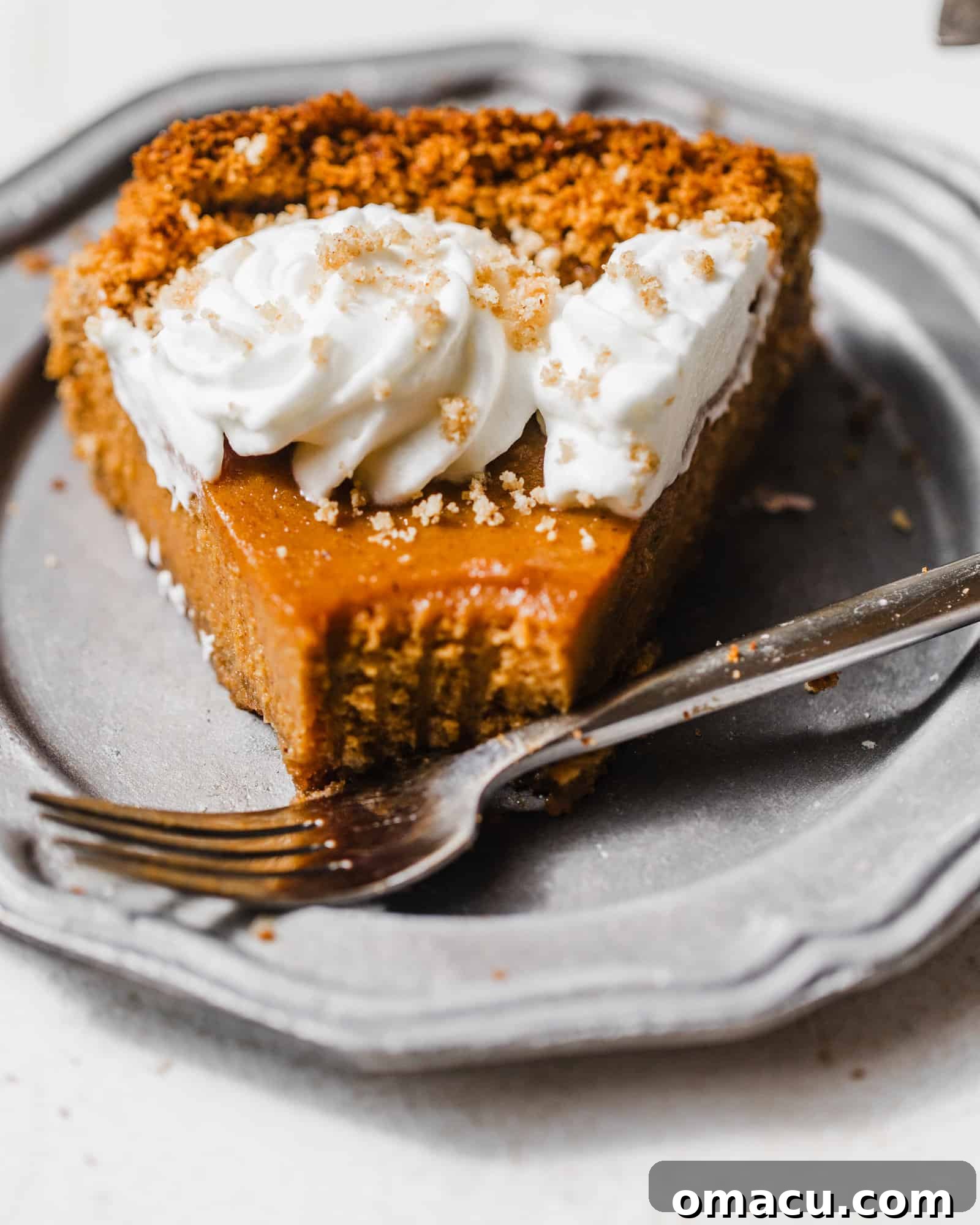 a slice of graham cracker sweet potato pie on a silver plate with a fork