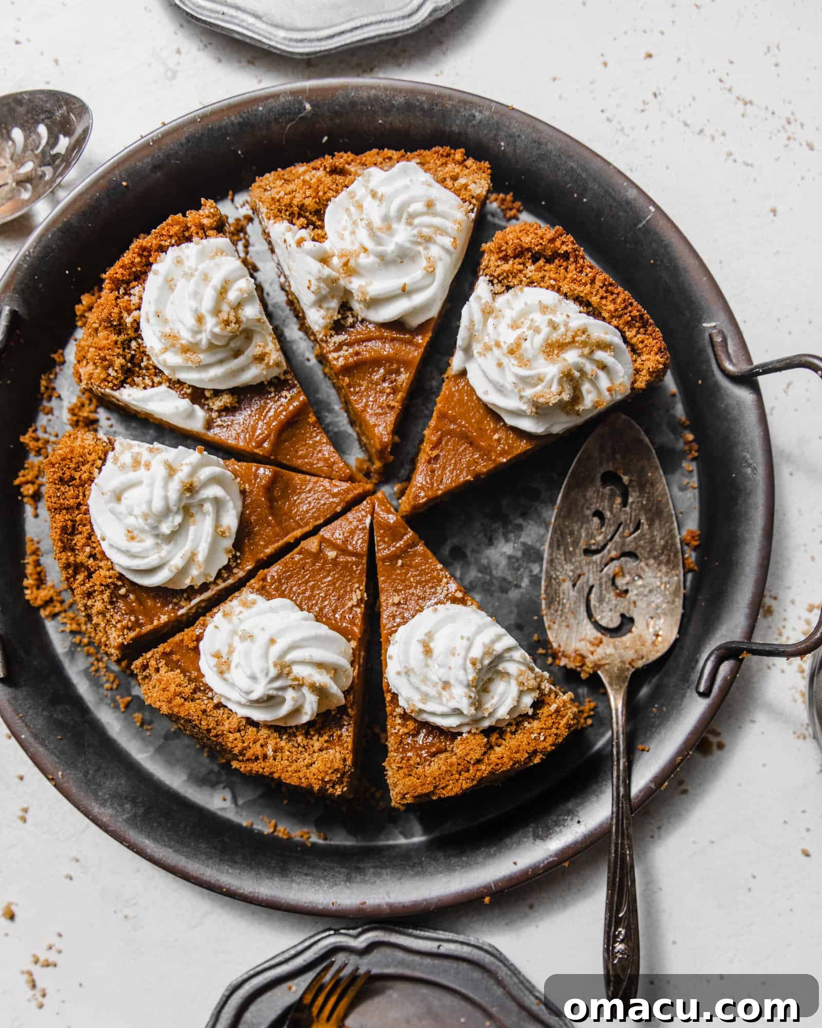 sliced sweet potato pie with graham cracker crust on a silver platter topped with whipped cream