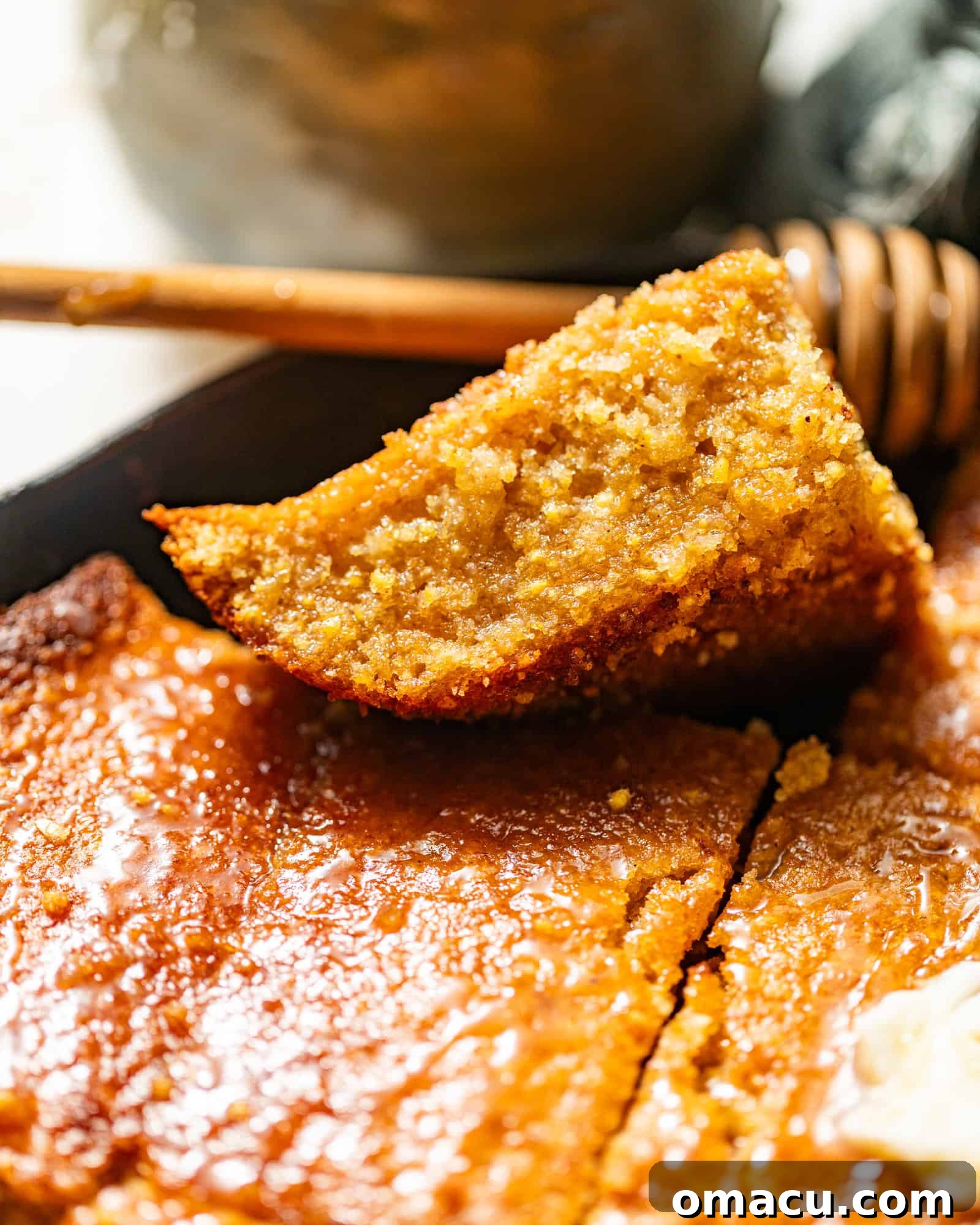 An up-close photo of a perfectly baked slice of golden cornbread, showing its moist crumb.