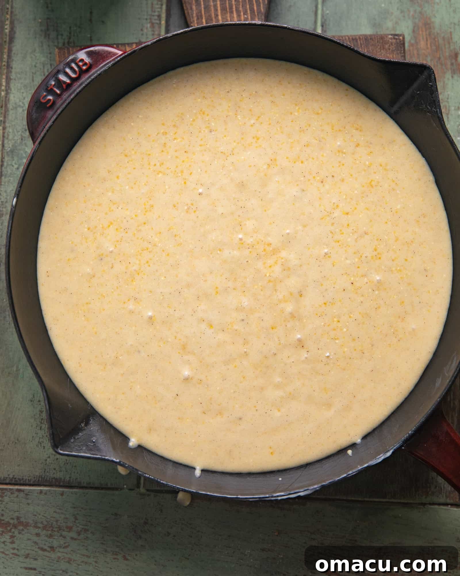 Smooth cornbread batter poured into a cast iron skillet, ready for baking.