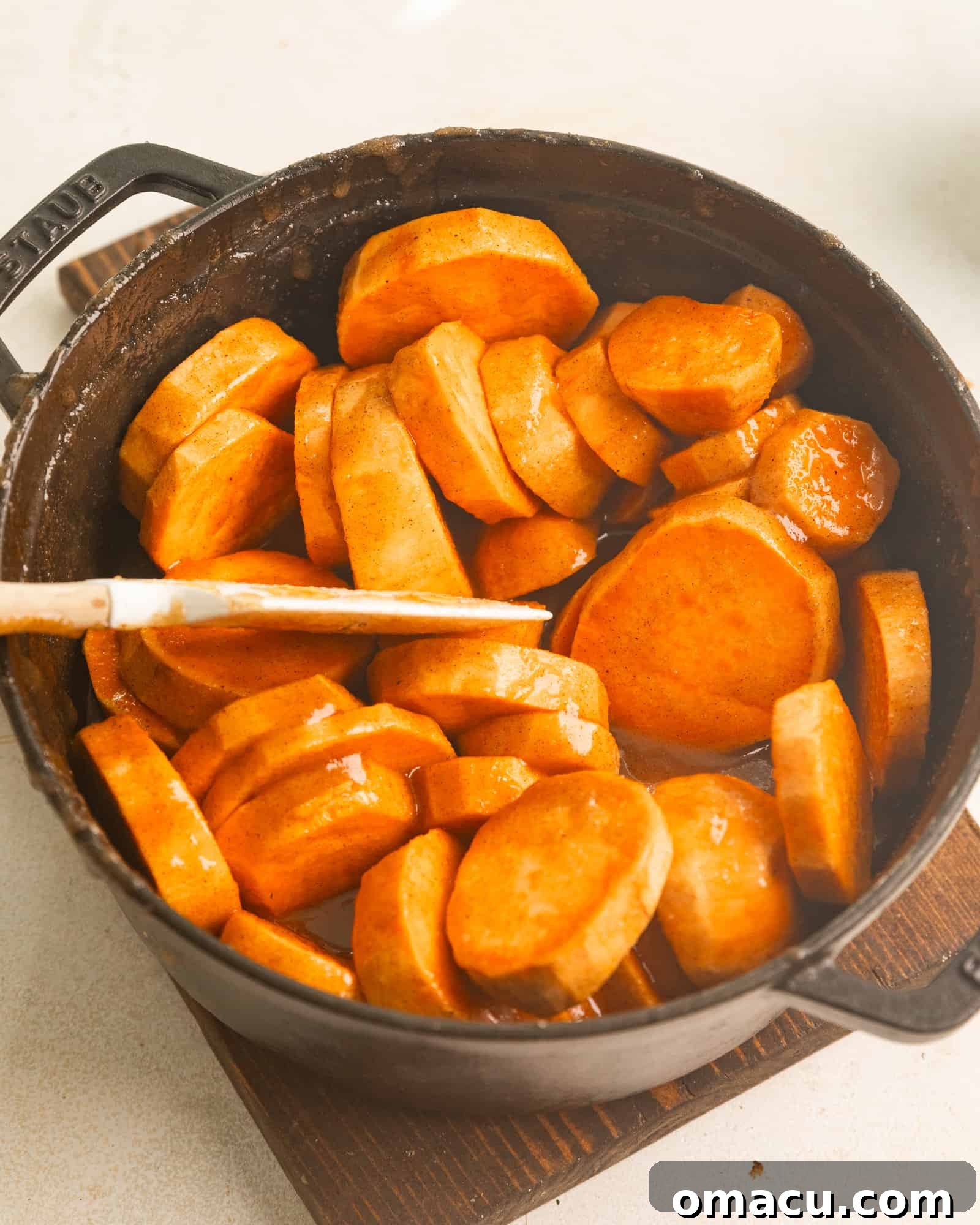 Sliced sweet potatoes carefully arranged in a large pot, generously coated in the rich, spiced brown sugar syrup and melted butter.