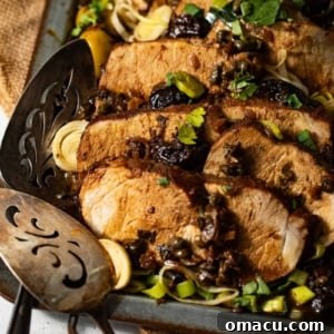 Pork Marbella in a serving dish, garnished with fresh herbs and sauce.