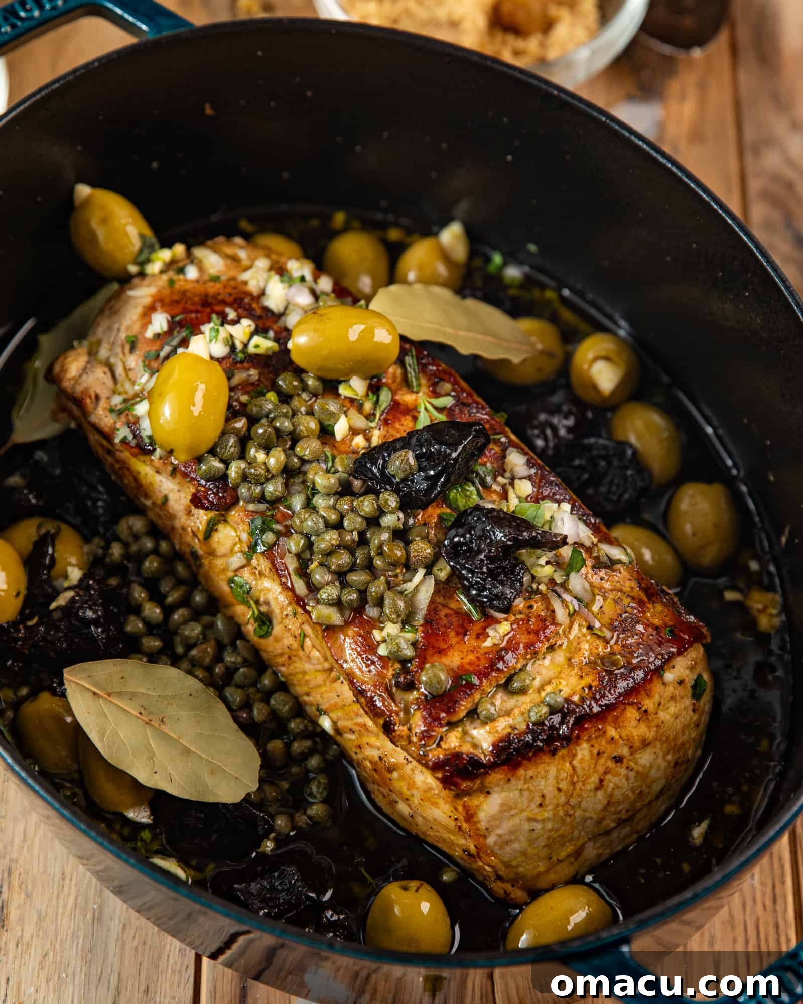Pork tenderloin searing in a Dutch oven with vegetables and the olive oil marinade, showing the rich colors and textures during the cooking process.