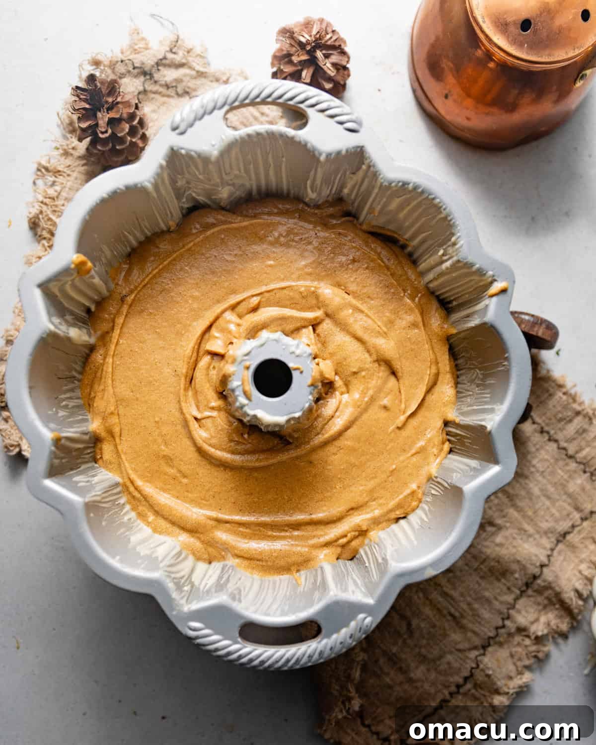 Gingerbread bundt cake batter has been smoothly poured into a well-greased bundt pan, ready for baking.