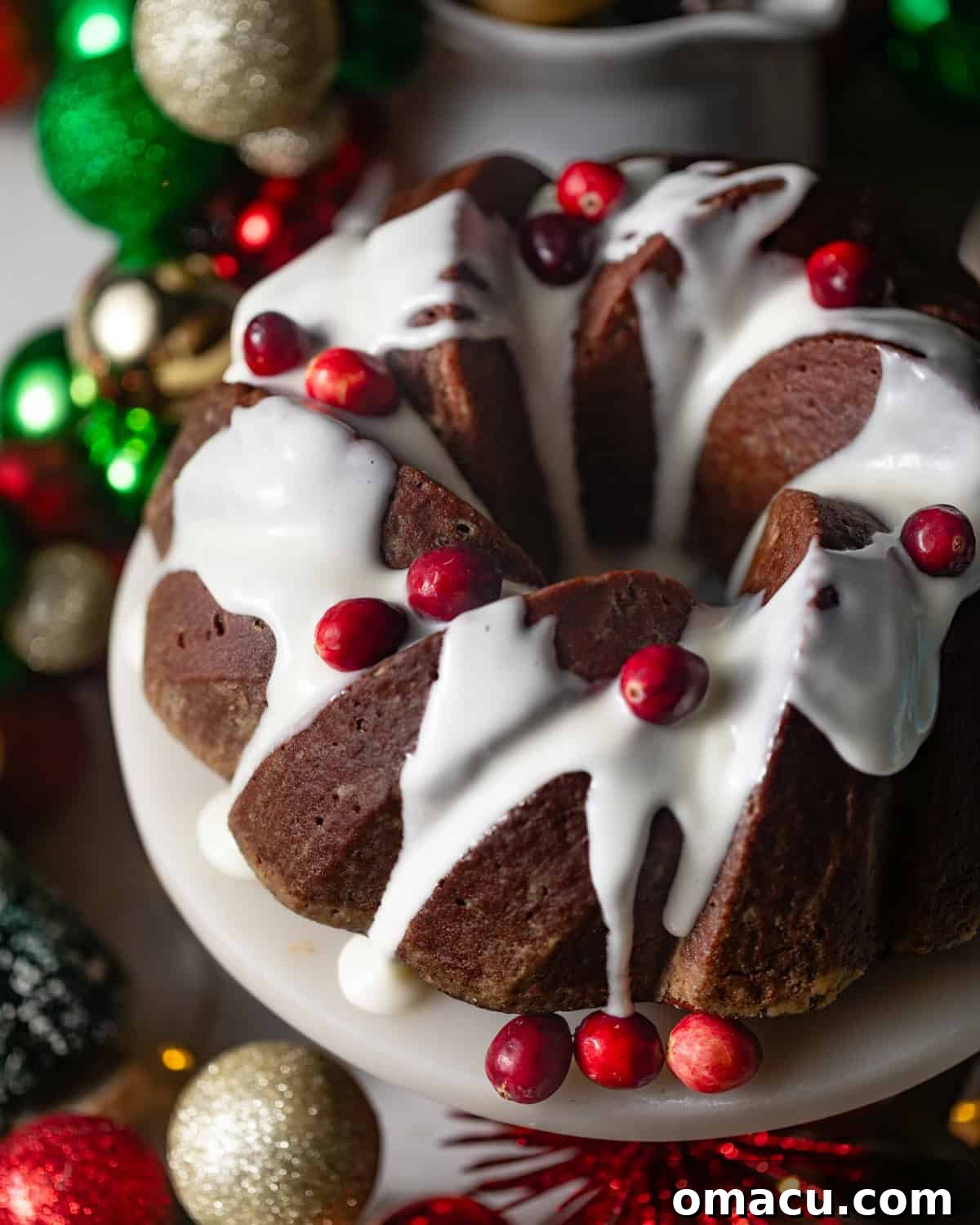 A gorgeous gingerbread bundt cake, generously topped with a smooth cream cheese frosting and garnished with fresh cranberries, perfect for a festive display.