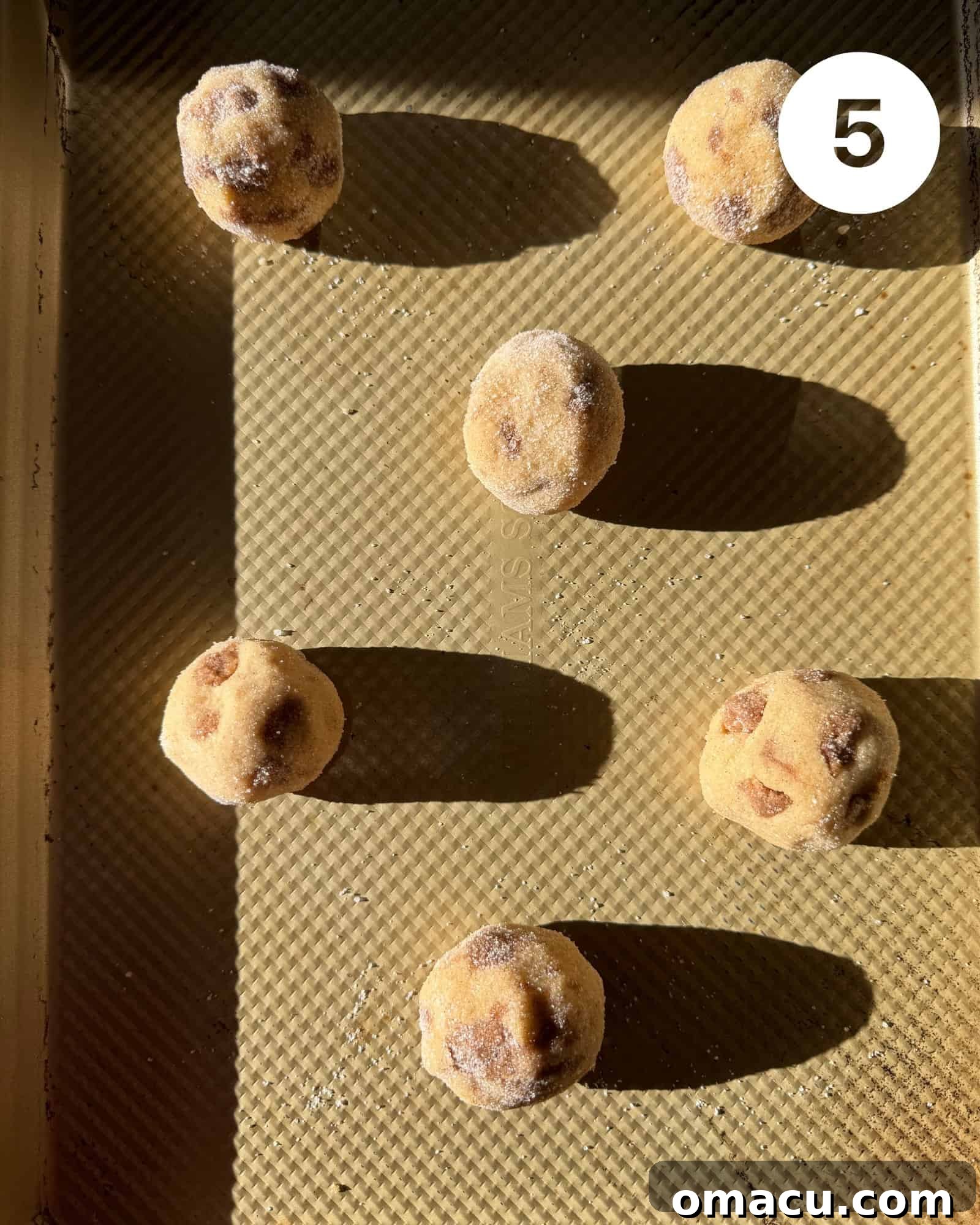 Cookie dough balls, perfectly spaced on a baking sheet lined with parchment paper, ready to go into the oven
