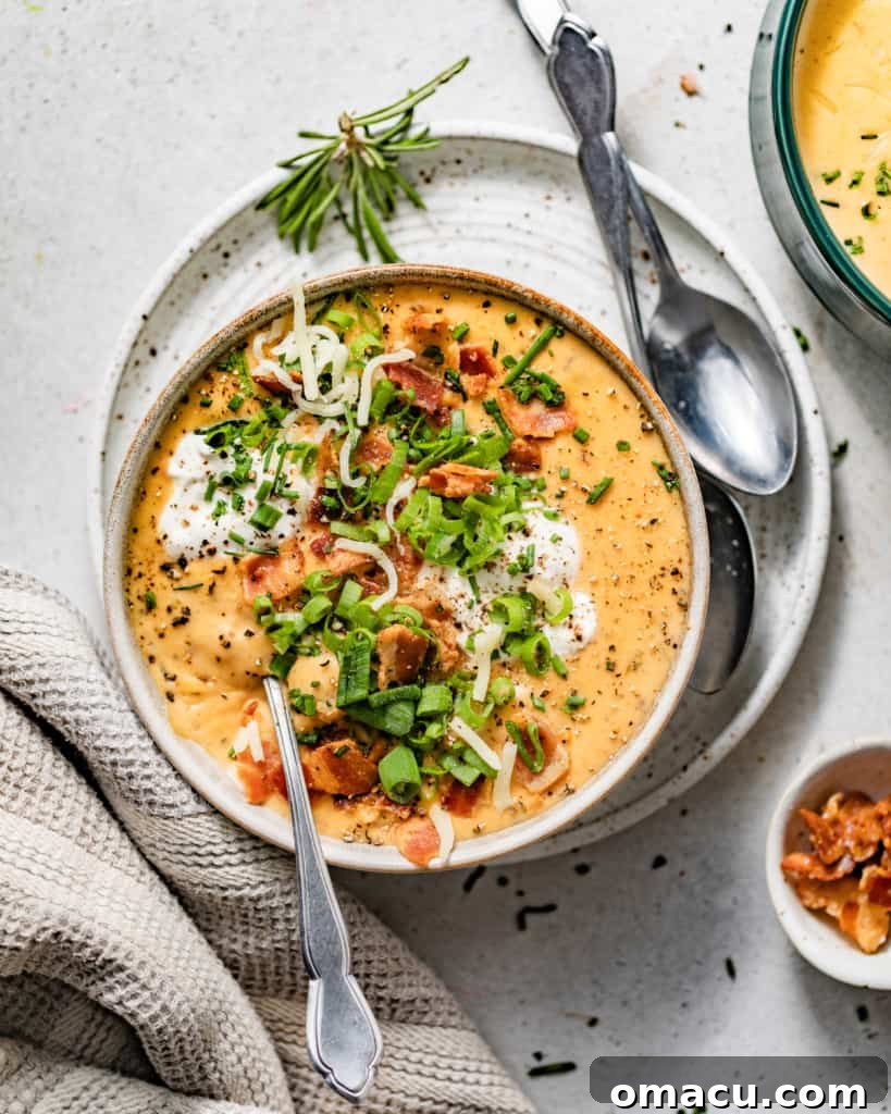 loaded baked potato soup in a white bowl topped with chives, bacon, sour cream, and shredded cheddar cheese